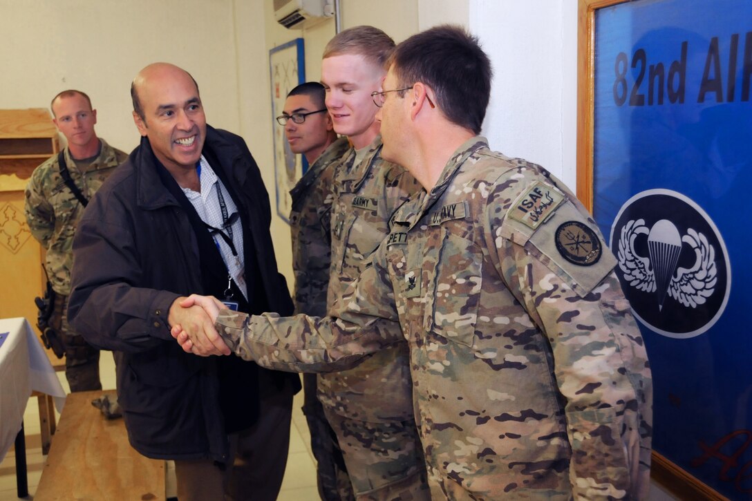 U.S. Ambassador Hugo Llorens, left, assistant chief of mission at the U.S. Embassy in Kabul, Afghanistan, shakes hands with U.S. Navy Petty Officer 2nd Class Sean Petty, right, after breakfast with troops on Forward Operating Base Farah in Farah City, Afghanistan, Feb. 6, 2013. Petty, a logistics specialist, is assigned to Provincial Reconstruction Team Farah.
