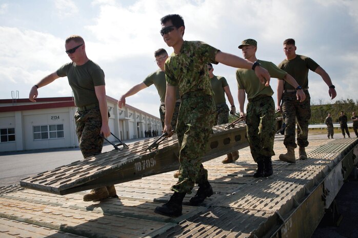Japan Ground Self-Defense Force 2nd Lt. Akihiro Oyabu (center) helps carry a ramp to the end of a medium-girder bridge Marines and JGSDF members constructed Feb. 1 at Camp Hansen. JGSDF officers spent time with 9th Engineer Support Battalion over a five-week period, learning the different aspects and functions of 9th ESB. Oyabu is an infantryman with 12th Infantry Regiment, 8th Division, Western Army, JGSDF. The Marines are with 9th ESB, 3rd Marine Logistics Group, III Marine Expeditionary Force
 