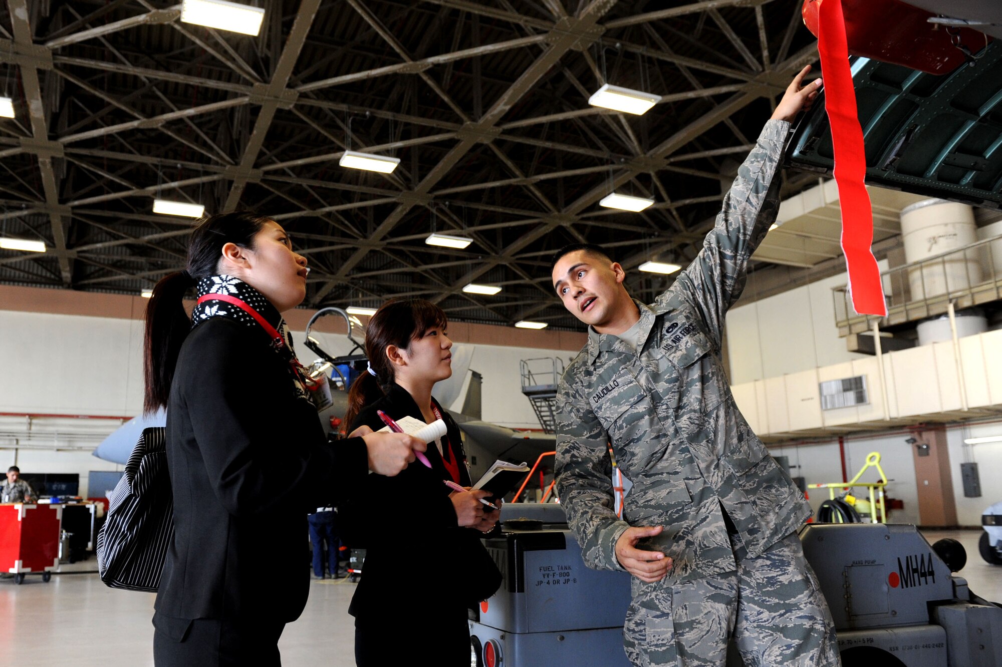 U.S. Air Force Senior Airman Nick Caudillo, 18th Equipment Maintenance Squadron crew chief, explains to Saki and Miki, Nikkei College of Business students, how technical orders are important on Kadena Air Base, Japan, Jan. 31, 2013. The students participated in a five-day English conversation exchange program and toured different squadrons around base. (U.S. Air Force photo/Airman 1st Class Brooke P. Doyle)