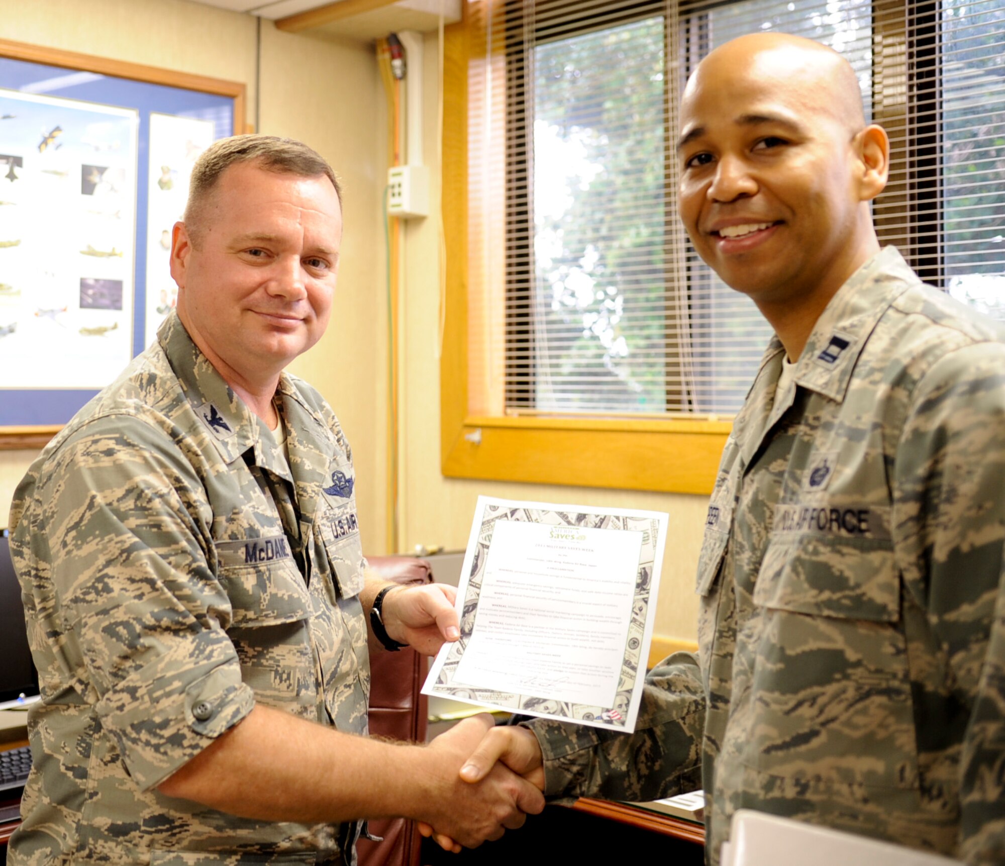 U.S. Air Force Col. Brian McDaniel, 18th Wing vice commander, shakes hands with Capt. Leo Green, 18th Force Support squadron force support officer, after McDaniel signed the Military Saves Week proclamation at the 18th Wing headquarters building on Kadena Air Base, Japan, Feb. 6, 2013. Military Saves Week is a time for military members to focus on saving money. (U.S. Air Force photo/Naoto Anazawa)