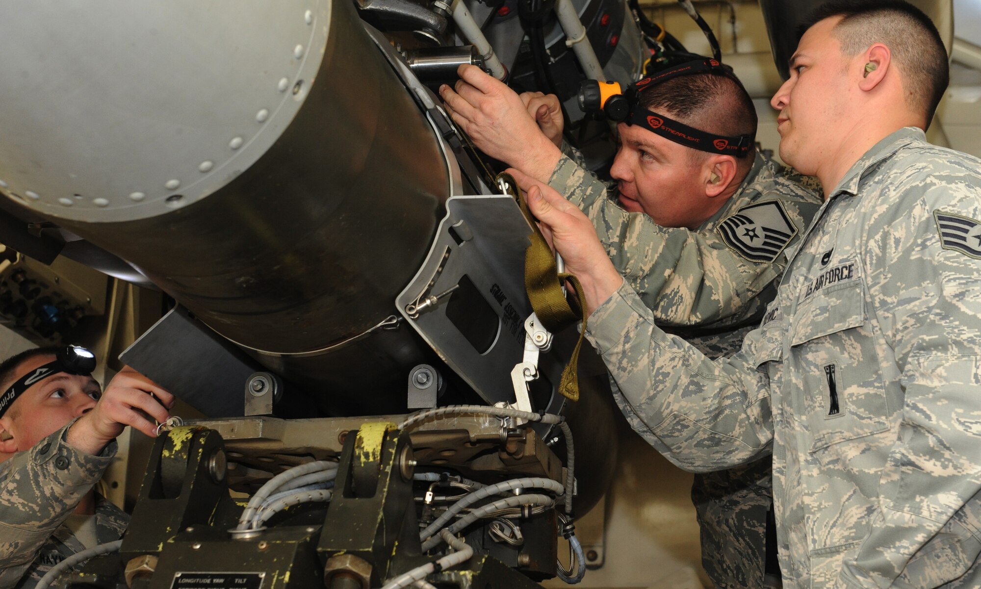 WHITEMAN AIR FORCE BASE, Mo -- Tech. Sgt. Johnathan Haynes, Master Sgt. Christopher McFatridge, and Staff Sgt. Stephan Capkovic, 131st Aircraft Maintenance Squadron load crew team members, lock a mock GBU-31 into place during the Load Crew of the Year competition, Jan. 25. The purpose of the load competition is to get the airmen to strive for excellence and to get extra time to practice handling weapons. (U.S. Air Force photo/Airman 1st Class Bryan Crane)