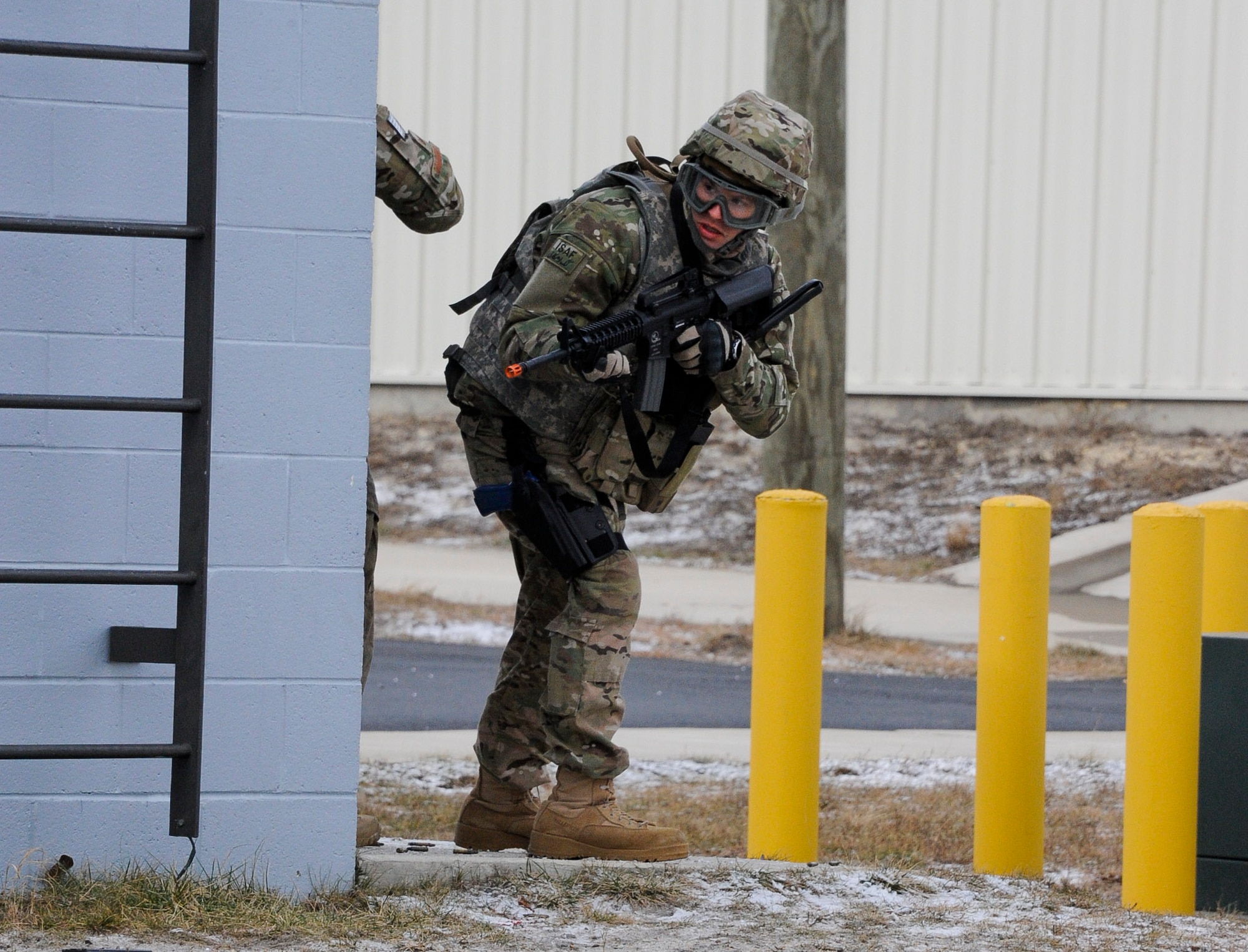 An Air Advisor Academy student looks around a corner for advancing enemy forces Feb. 1, 2013, on the ranges at Joint Base McGuire-Dix-Lakehurst, N.J., as part of their field training exercise. The students used the urban environment to their advantage by using the buildings for cover against enemy attack. (U.S. Air Force photo by Airman 1st Class Ryan Throneberry/Released)