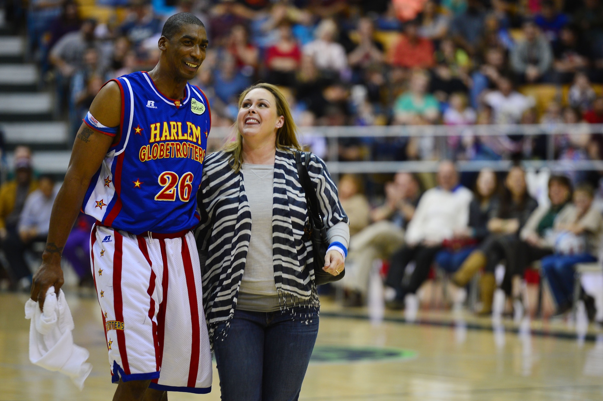 Hi-Lite Bruton, forward for the Harlem Globetrotters, walks off court with the spouse of U.S. Air Force Lt. Col. Chester Dooly, 73rd Special Operations Squadron director of operations, during an intermission of a basketball game at the Greyhound Arena in Portales, N.M., Feb. 5, 2013. The Harlem Globetrotters offered a crowd of several hundred people a comical, energy-packed game. (U.S. Air Force photo/Airman 1st Class Eboni Reece)