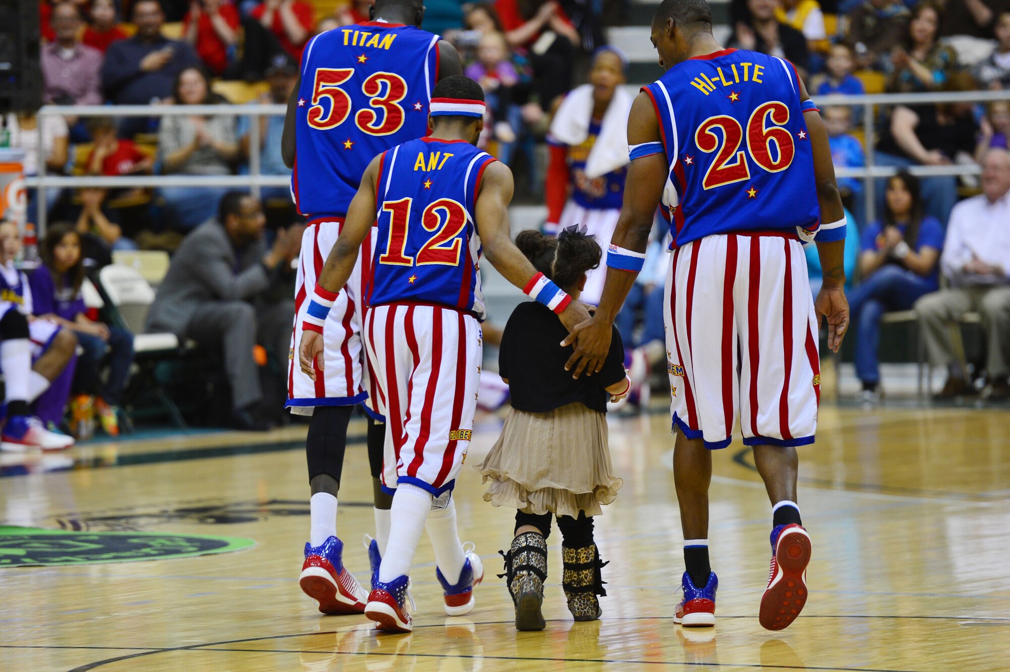 Members of the Harlem Globetrotters basketball team walk off the court with a young spectator during an intermission of a basketball game at the Greyhound Arena in Portales, N.M., Feb. 5, 2013. The Harlem Globetrotters offered a crowd of several hundred people a comical, energy-packed game. (U.S. Air Force photo/Airman 1st Class Eboni Reece)