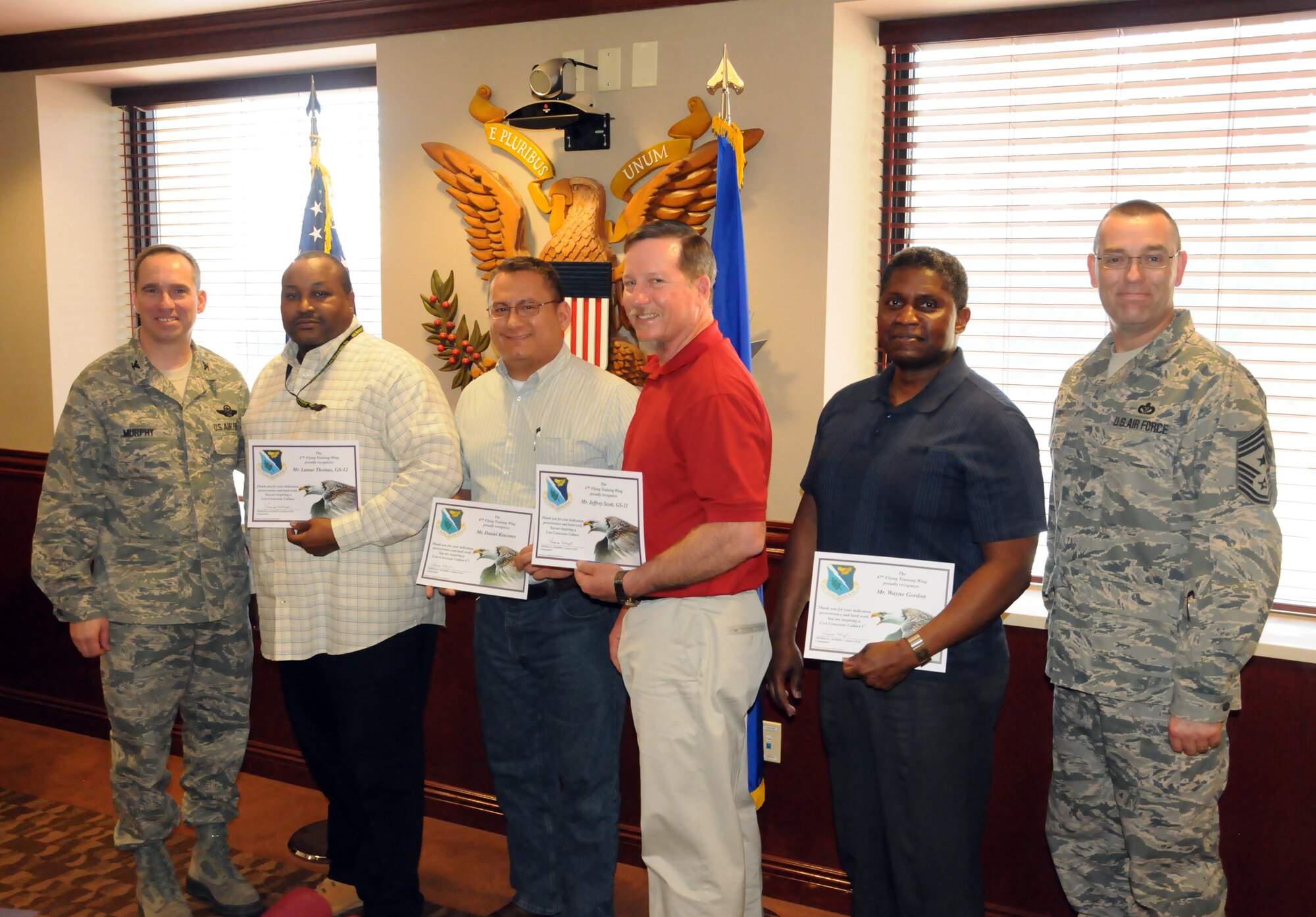 Lamar Thomas, 47th Communication Squadron flight chief, along with team members Jeff Scott, Dan Rincones and Wayne Gordon, pose with Col. Tom Murphy, 47th Flying Training Wing commander, and Chief Master Sgt. Garry Berry, 47th FTW command chief, after receiving the Cost Conscious Culture Award at Laughlin Air Force Base, Texas, Feb. 5, 2013. The team was recognized for promoting an idea that saved more than $675,000 while updating vital infrastructure in the process. (U.S. Air Force photo/Joel Langton)
