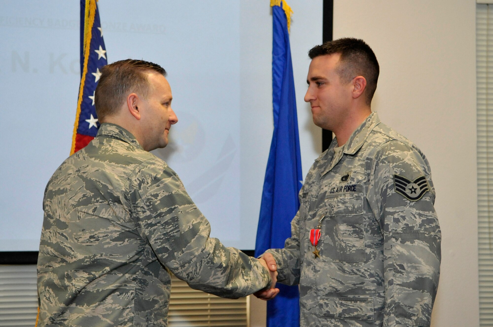 Col. Richard Williamson, 305th Air Mobility Wing commander, awards Staff Sgt. Mark Kosisky, 305th Aerial Port Squadron air transportation journeyman, the Bronze Star Medal Jan. 31, 2013, at the Passenger Terminal on Joint Base McGuire-Dix-Lakehurst, N.J. Kosisky received the award for his exceptional meritorious service in support of Operation Enduring Freedom and his outstanding dedication to duty during combat operations in Afghanistan he was also awarded the Defense Intelligence Emblem of Honor from the Romanian Ministry of National Defense and the German Armed Forces Proficiency Badge, Bronze award during the ceremoney. Kosisky hails from Jenkins township, Pa.  (U.S. Air Force photo by Wayne Russell/Released)