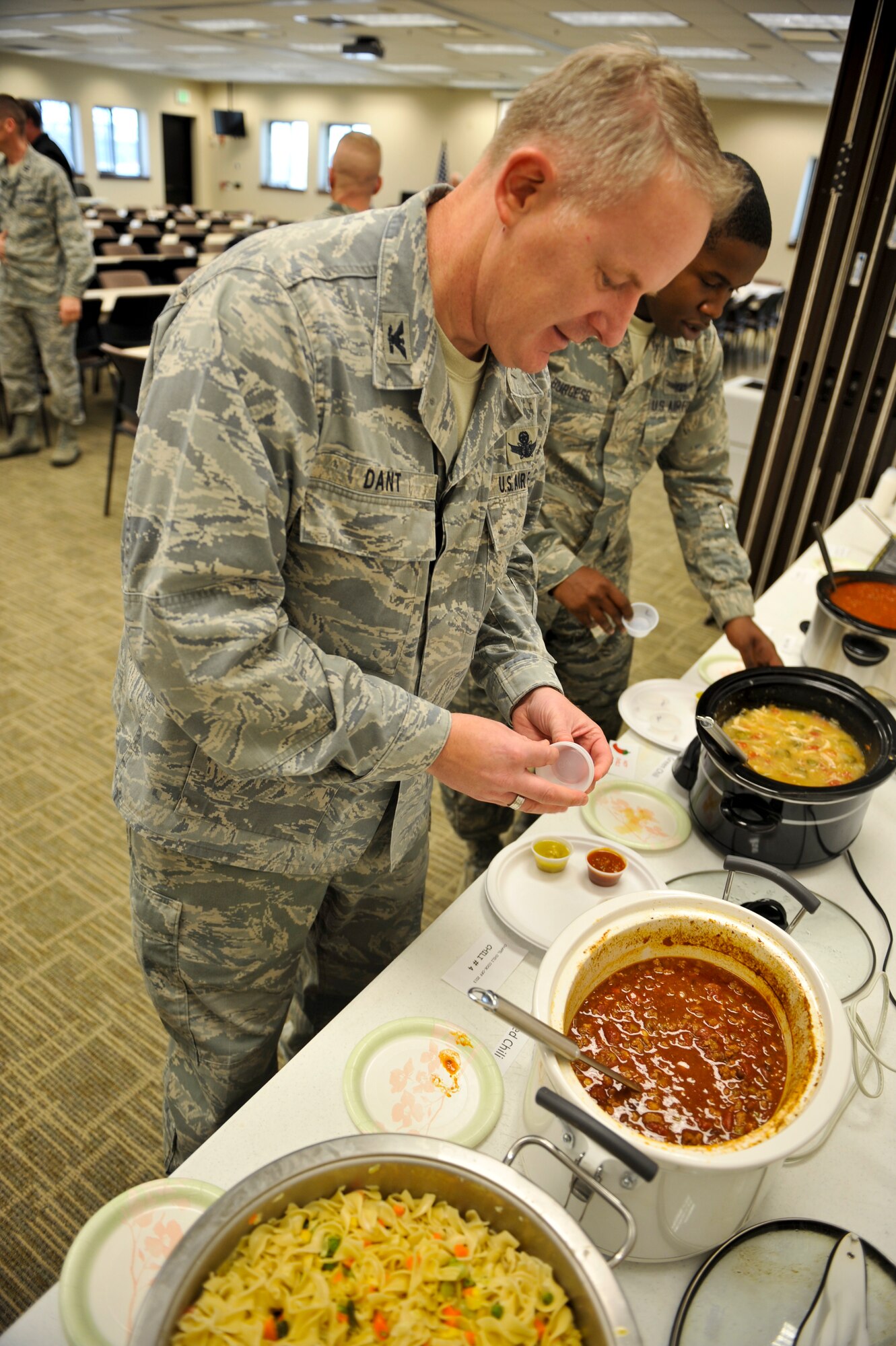 Col. Dan Dant, 460th Space Wing commander, grabs a sample of chili at the 10th Annual Chili Cook-Off hosted by the Buckley Air Force Base Chapel Feb. 6, 2013, at the chapel Fellowship Hall. Dant was one of six judges for the cook-off. There were 16 entries in the competition, nearly double last year’s submissions. (U.S. Air Force photo by Airman 1st Class Riley Johnson/Released)