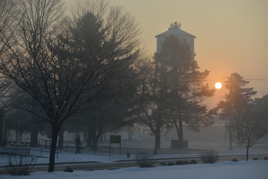 As the sun rises through the morning fog, Lori Boucher, 439th Conference Center Director, prepares to shovel a bit of snow that fell overnight on January 6, 2013. (U.S. Air Force photo by W.C. Pope) 