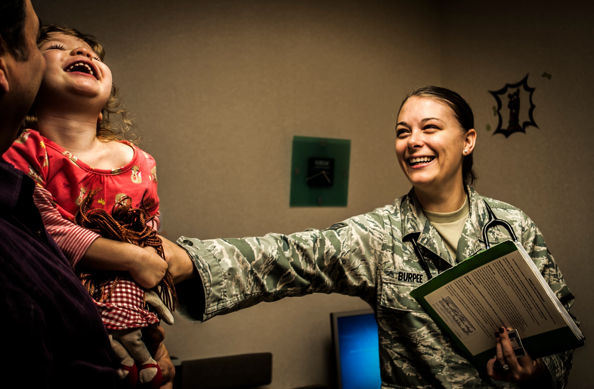 Senior Airman Melinda Burpee, 628th Medical Group aerospace medical technician,  entertains two-year-old Olivia Miller before she meets with the doctor during a routine check-up Feb. 1, 2013, at Joint Base Charleston – Air Base, S.C. Olivia is the daughter of Maj. Tami Miller, Family Nurse Practitioner flight commander. The   628th MDG pediatricians support Airmen by guiding, and assisting families through the physical, mental and emotional growth of children, as well as treating illness. (U.S. Air Force illustration / Airman 1st Class Tom Brading)   