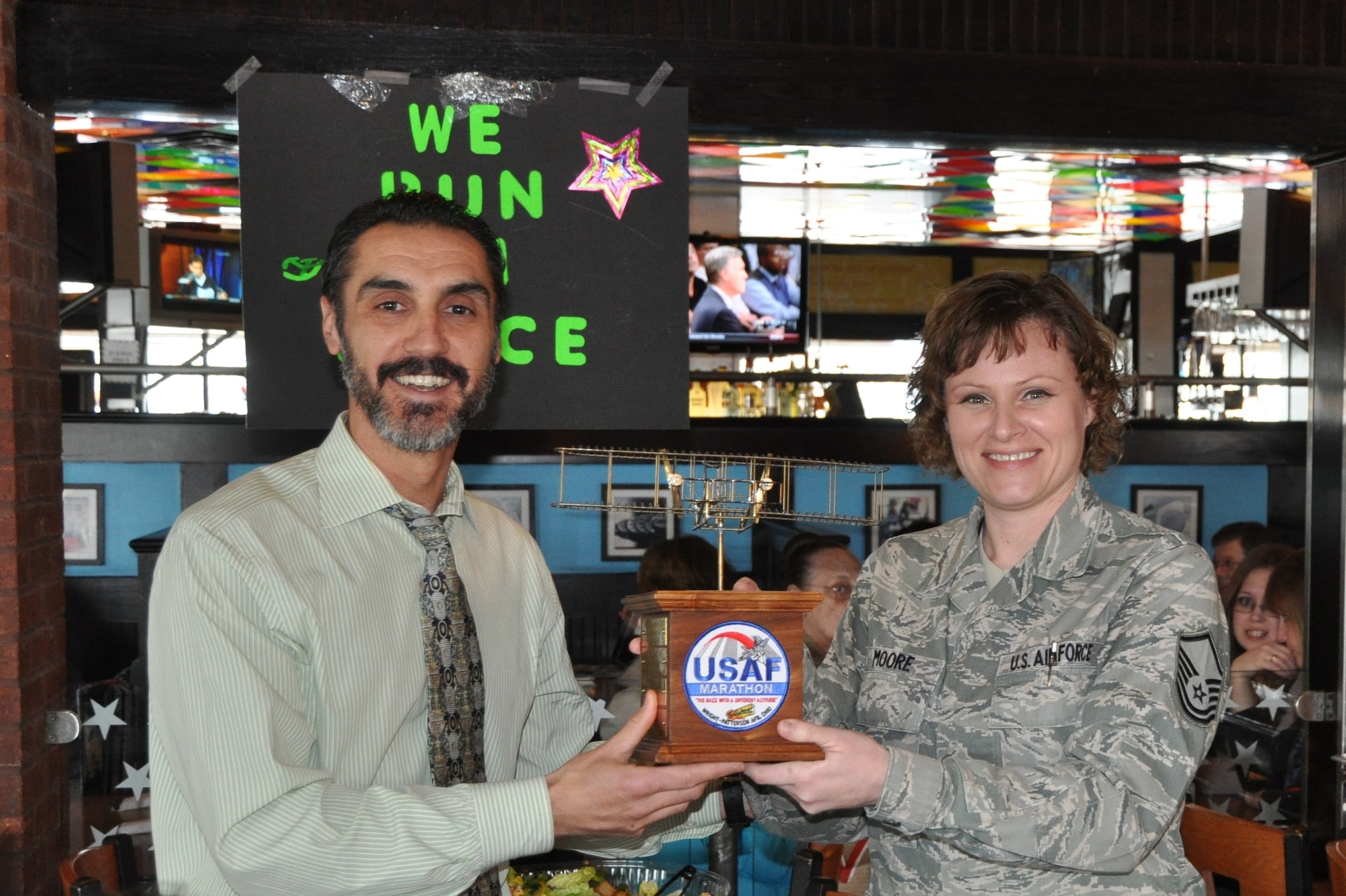 Air Force Marathon Race Director Rob Aguiar presents the best Hydration Station trophy to Master Sgt. Sally Moore from the National Air and Space Intelligence Center for their alien station theme for the 2012 U.S. Air Force Marathon.  Volunteers dressed up as aliens and welcomed runners to NASIC’s Alien Nation. (US Air Force photo)