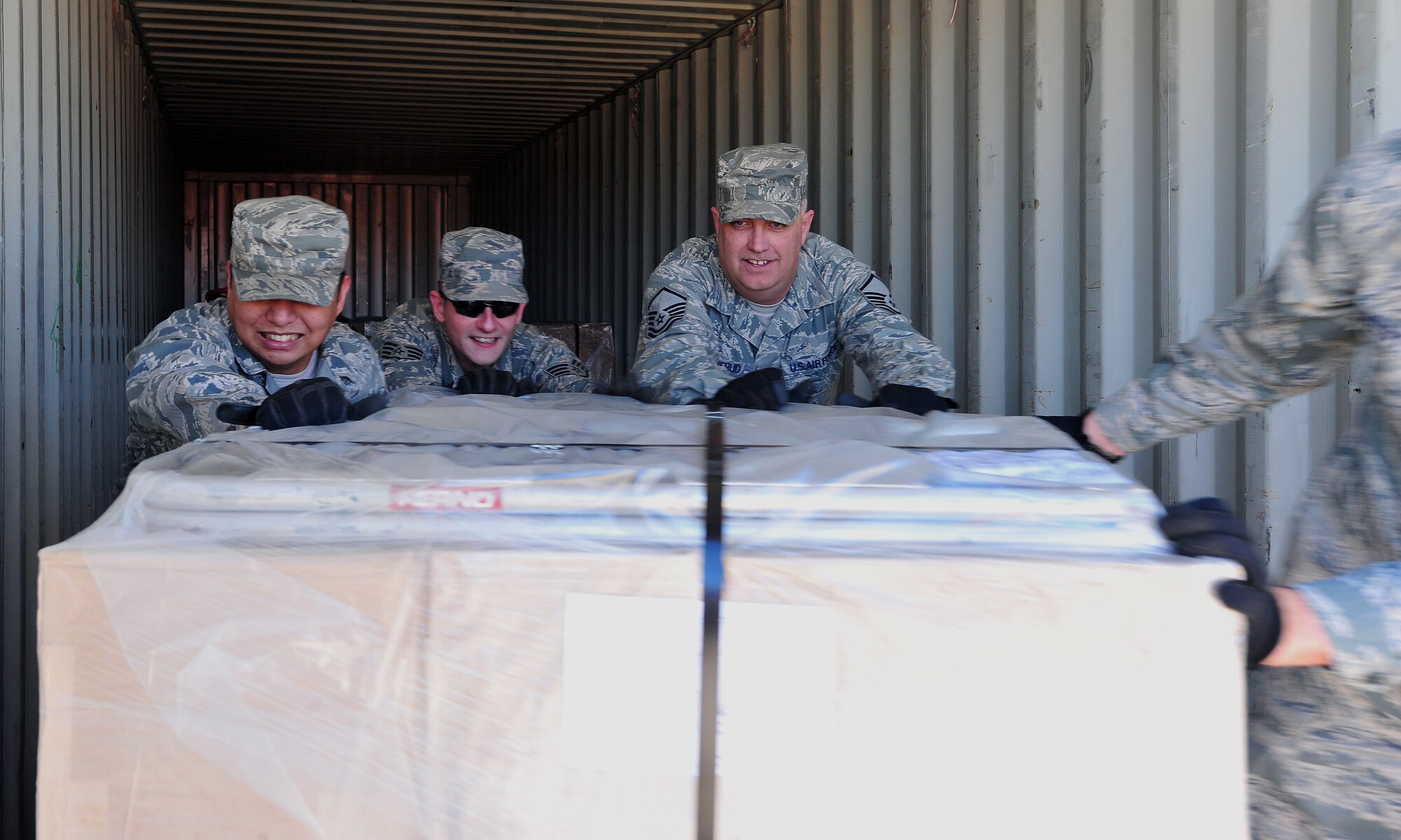(Left to right) Staff Sgt. Kris Aguila, Staff Sgt. Michael Weaver, and Master Sgt. Brian Saverud, 22nd Logistics Readiness Squadron air transportation, push a pallet from out of a shipping container at the Wichita Fire Department Training Center Feb. 4, 2013, Wichita, Kan. Approximately 17 pallets were transferred from the training center to McConnell Air Force Base as a part of a humanitarian shipment to Paraguay. (U.S. Air Force photo/Airman 1st Class Colby L. Hardin)