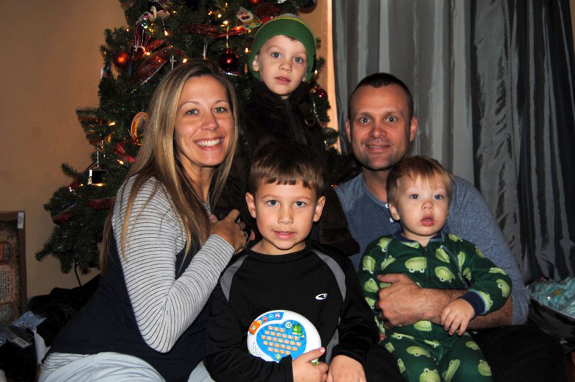 Sara Jane (left), Gammon (bottom center), Harrison (top center), U.S. Army Capt. Sam Arnett (top right) and Levi Arnett (bottom right) pose for a photo in their home in Newport News, Va., during Capt. Arnett’s mid-deployment leave in December 2012.  Capt. Arnett is currently deployed to Camp Buehring, Kuwait. (Courtesy photo/Released)