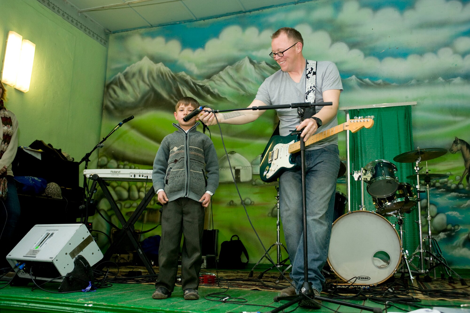 Staff Sgt. Josh Byrd, U.S. Air Forces Central Command Band guitarist and vocalist, adjusts the microphone for a Kyrgyz child during a show at the Chui Orphanage-Boarding School in Bishkek, Kyrgyzstan, Jan. 29, 2013. Following the band's concert, students at the school returned the favor and performed traditional Kyrgyz music for members of the band. (U.S. Air Force photo/Staff Sgt. Stephanie Rubi)