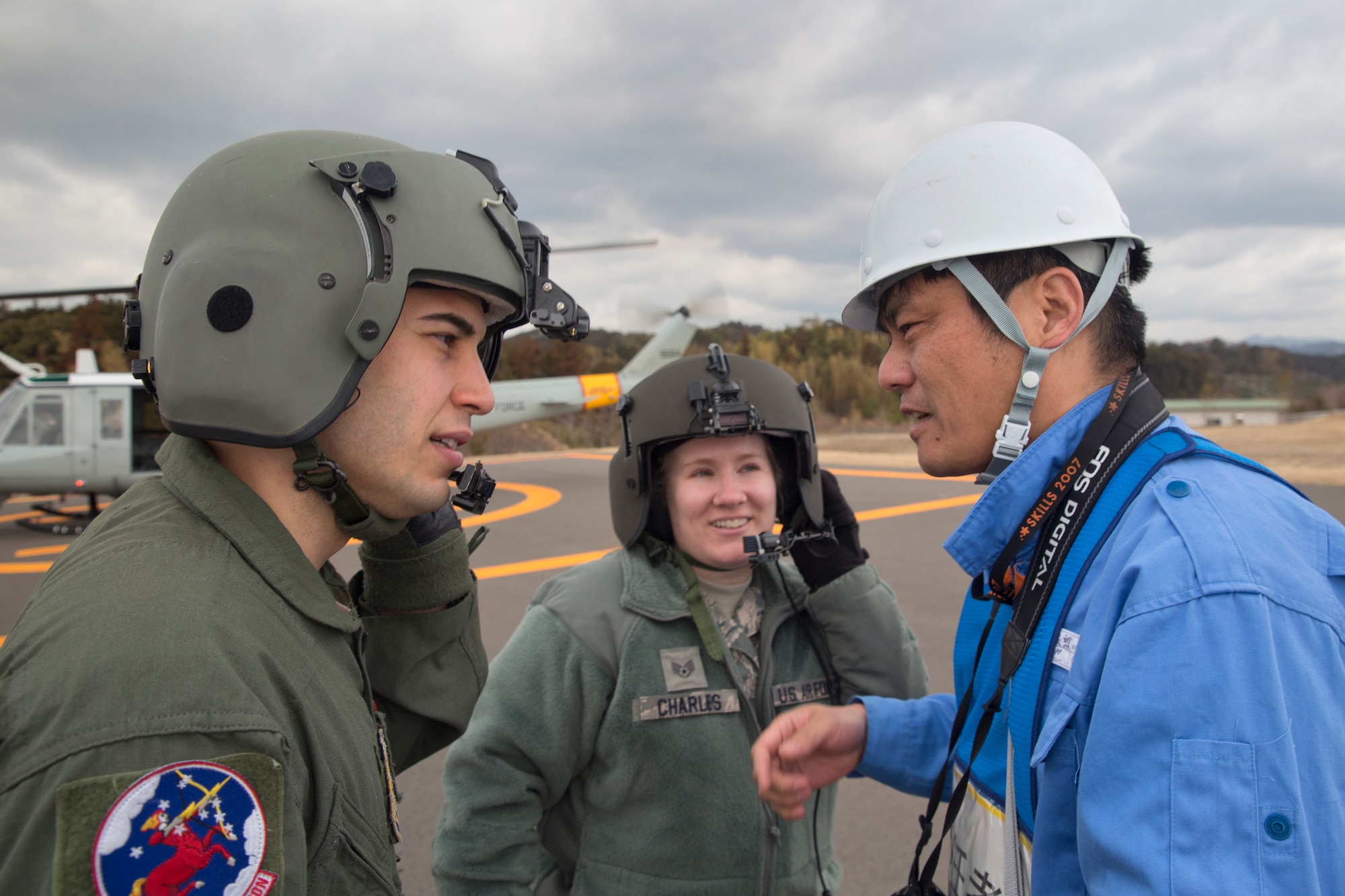SHIZUOKA PREFECTURE, Japan -- From left to right, Staff Sgt. Arturo Fernandez, 459th Airlift Squadron flight engineer, and Staff Sgt. Leslie Charles, 374th Medical Operations Squadron independent duty medical technician, talk to a member from the Shizuoka Prefectural Government after landing the Shin-tomei expressway's service area by a UH-1 Huey at Shizuoka Prefecture, Japan, Feb. 5, 2013. (U.S. Air Force photo by Osakabe Yasuo)