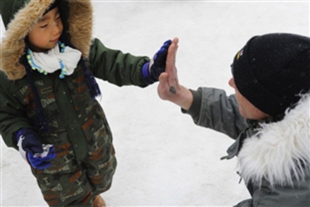 U.S. Navy Chief Christopher "Billy" Knox gives a high five to a child at the 64th annual Sapporo Snow Festival in Sapporo, Japan, Feb. 4, 2013. Knox, the leader of the Navy Misawa Snow Team, and team members created a snow sculpture of the USS George Washington on behalf of the base for the festival on Japan’s Hokkaido Island. This was the 30th year the naval installation sent a delegation of sailors to take part in the event.