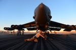 Air Force Senior Airman John Myer pushes a tow bar under the tire of a B-52H Stratofortress at Nellis Air Force Base, Nevada. 