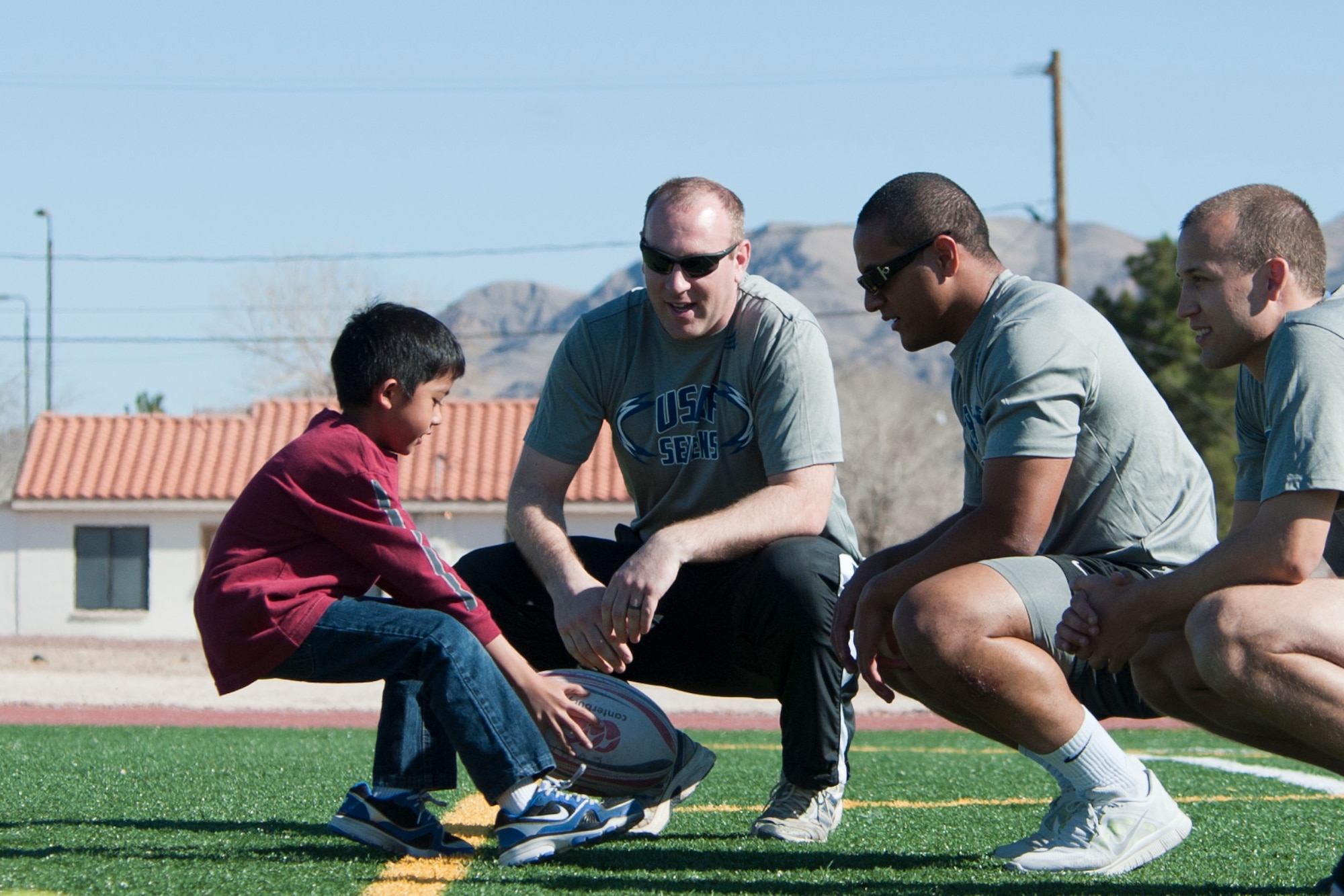 A Lomie Heard Elementary School student practices sprinting drills as Air Force Rugby Sevens players look on during a children's rugby clinic Feb. 6, 2013, at Nellis Air Force Base, Nev.  Armed forces Rugby Sevens teams from all four branches of service are participating in the largest amateur rugby tournament in Las Vegas. (U.S. Air Force photo by Lawrence Crespo)