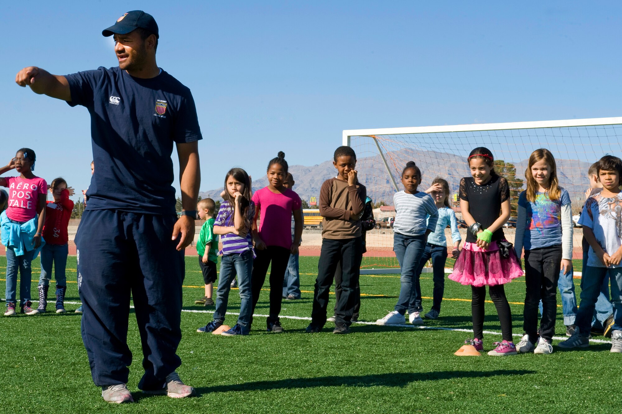 Vaha Esikia, USA Eagles Sevens player and coach, explains a lateral passing technique to Lomie Heard Elementary School students during the children's rugby clinic Feb. 6, 2013, at Nellis Air Force Base, Nev. Rugby sevens, also known as seven-a-side or VIIs, is a variant of rugby union in which teams are made up of seven players, instead of the usual 15. (U.S. Air Force photo by Senior Airman Matthew Lancaster)