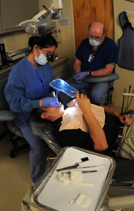 Capt. Kimberly Quilao (left), 9th Aerospace Medical Dental Squadron general dentist, and Mr. Richard LaCarney, 9th AMDS dental assistant, use a transilluminator to check for cracks in a patient's teeth at the dental clinic on Beale Air Force Base Calif., Feb. 8, 2013. If untreated cracked tooth syndrome can lead to severe pain, possible pulpal death, abscess, and even the loss of the tooth. (U.S. Air Force photo by Senior Airman Allen Pollard/Released)