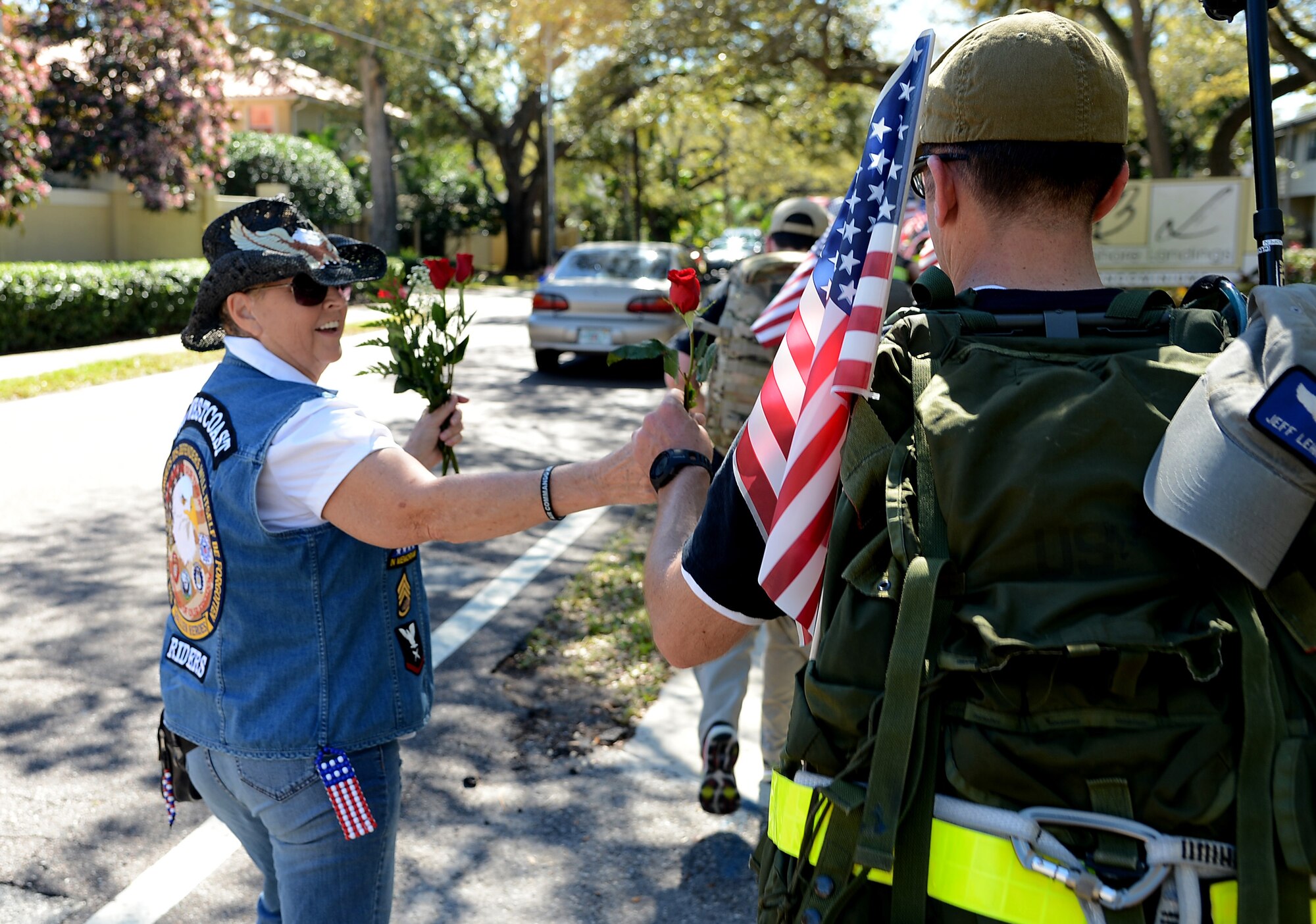 A Patriot Guard Rider hands a rose to an Airman along Bayshore boulevard Tampa Fla., on Feb. 8, 2013. Sixteen Airmen from Hurlburt Field, Fla. completed a 450-mile march in honor of five fallen Air Commandos. (U.S. Air Force photo by Airman 1st Class David Tracy/Released)