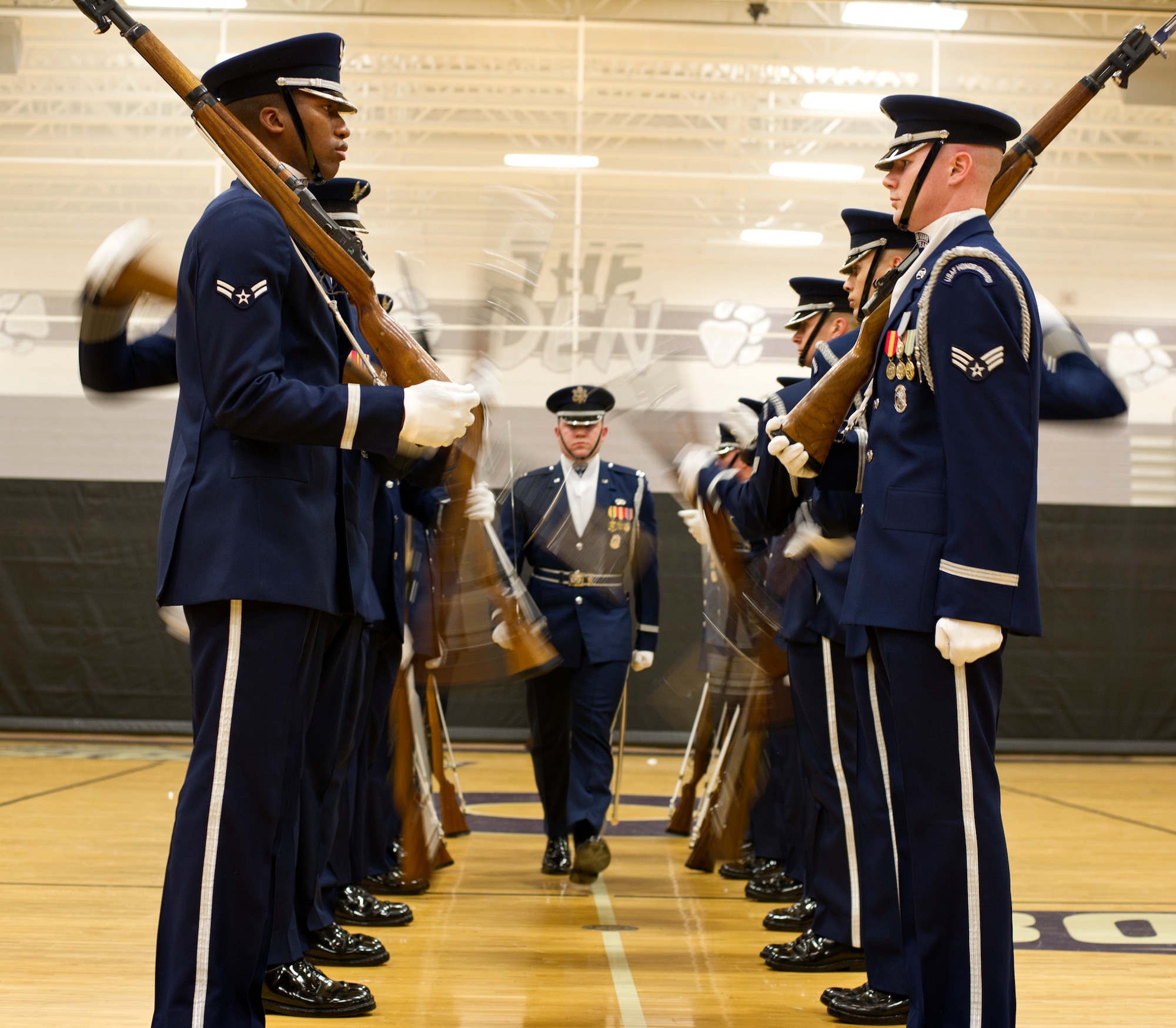 The U.S. Air Force Honor Guard Drill Team spins their weapons at full speed as Capt. Alexander Stanton, U.S. Air Force Honor Guard Drill Team commander, walks through during a performance at Battlefield High School on Feb. 6, 2013, in Haymarket, Va. The performance was Stanton’s final performance with the Drill Team. (U.S. Air Force photo/ Senior Airman Bahja Joi Jones)
