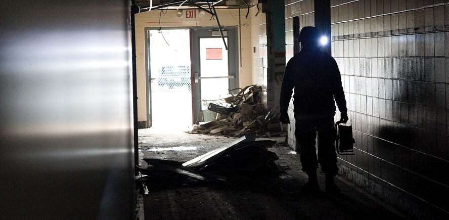 Senior Airman Gregg Lowry, a members of the 436th Civil Engineer Squadron, Explosive Ordnance Disposal (EOD) team, is partially silhouetted  while working inside a hallway of the former Arnold Elementary School during an EOD training event at Dover Air Force base, Del. on Feb. 7, 2013. Lowry has a Surefire tactical helmet light in-use to provide hands-free lighting while conducting critical mission tasks. The training allowed the Air Force EOD team to gain valuable training using live explosives during simulated events that mirror recent real-world scenarios encountered by EOD teams across the nation. The 436th CE Squadron also hosted regional law enforcement teams from the Delaware and New Jersey State Police. The civilian law enforcement and USAF teams exchanged ideas and best practices in the hands-on training to ensure all are safe and well prepared for the future. (U.S. Air Force photo/Greg L. Davis)     