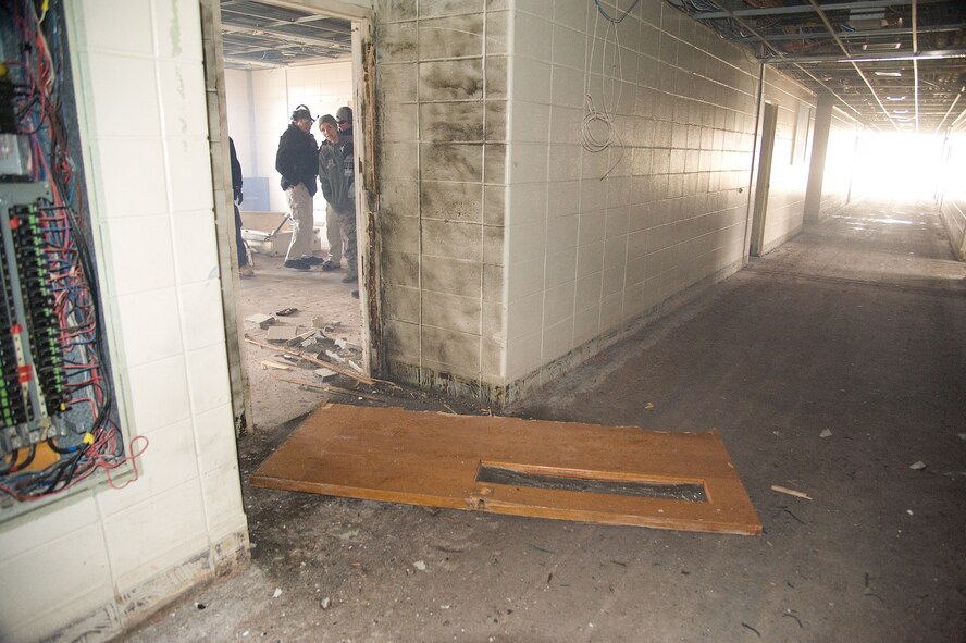 Military and civilian Explosive Ordnance Disposal (EOD) team members are framed by a door way as they discuss the effectiveness of a breaching charge that has blown the door off its hinges at Dover Air Force base, Del. on Feb. 7, 2013.  Members of the 436th Civil Engineer Squadron, EOD team conducted a training event that allowed the Air Force EOD team to gain valuable training using live explosives during simulated events that mirror recent real-world scenarios encountered by EOD teams across the nation. The 436th CE Squadron also hosted regional law enforcement teams from the Delaware and New Jersey State Police. The civilian law enforcement and USAF teams exchanged ideas and best practices in the hands-on training to ensure all are safe and well prepared for the future. USAF photo/Greg L. Davis   