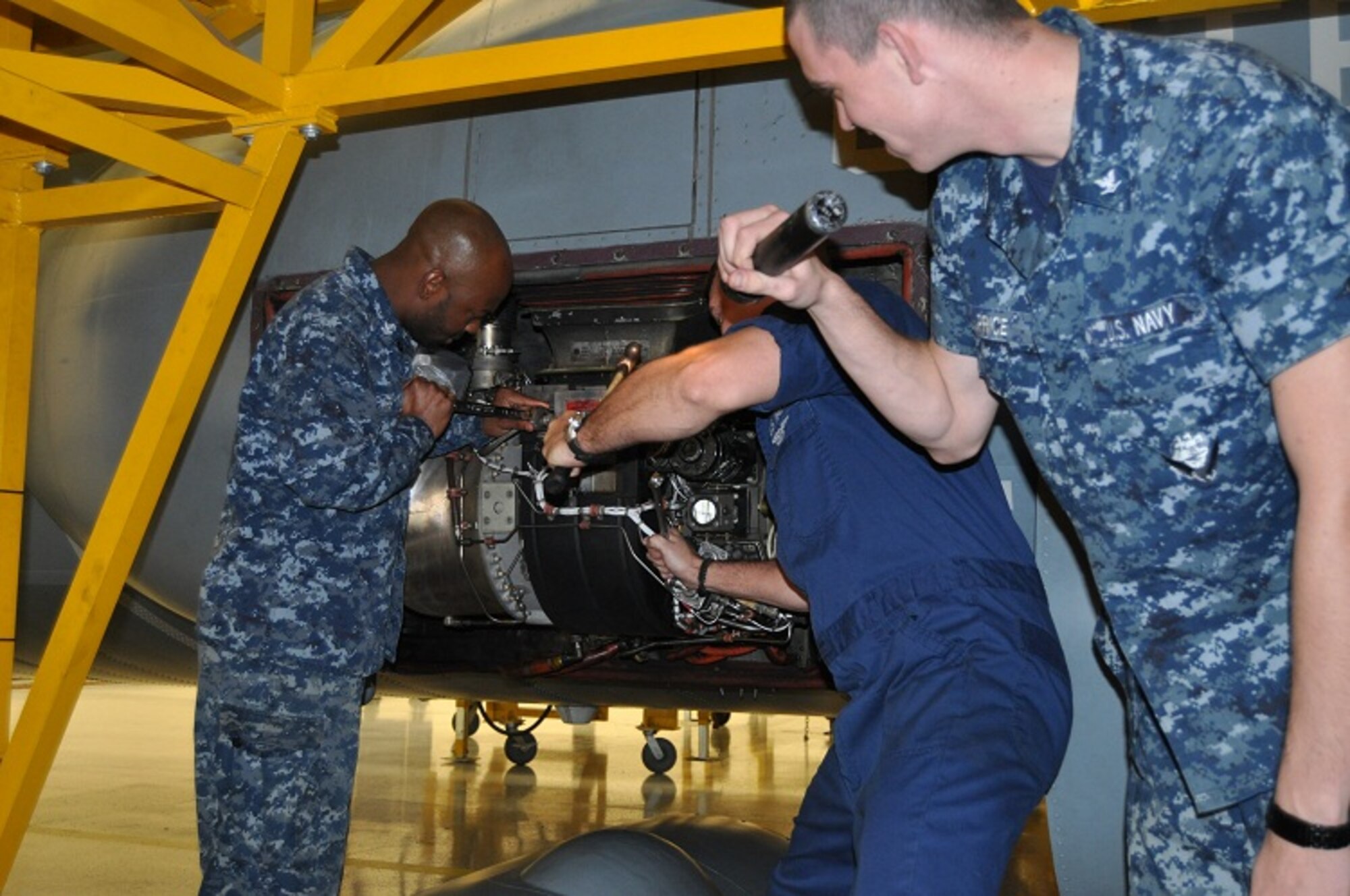 Petty Officer 2nd Class Michael Gensch, Navy Fleet Logistics Support Squadron VR-64 aircrewman, and Petty Officer 2nd Class Kevin Sears, VR-64 aviation machinist, repair a fuel line on the auxiliary power unit of a C-130T while Petty Officer 3rd Class James Price, VR-64 structural mechanic, provides light Feb. 5, 2013, inside the VR-64 hangar at Joint Base McGuire-Dix-Lakehurst, N.J. The constant upkeep of the C-130s allows VR-64 to maintain its around-the-clock naval air mobility mission. (U.S. Navy courtesy photo/Released)