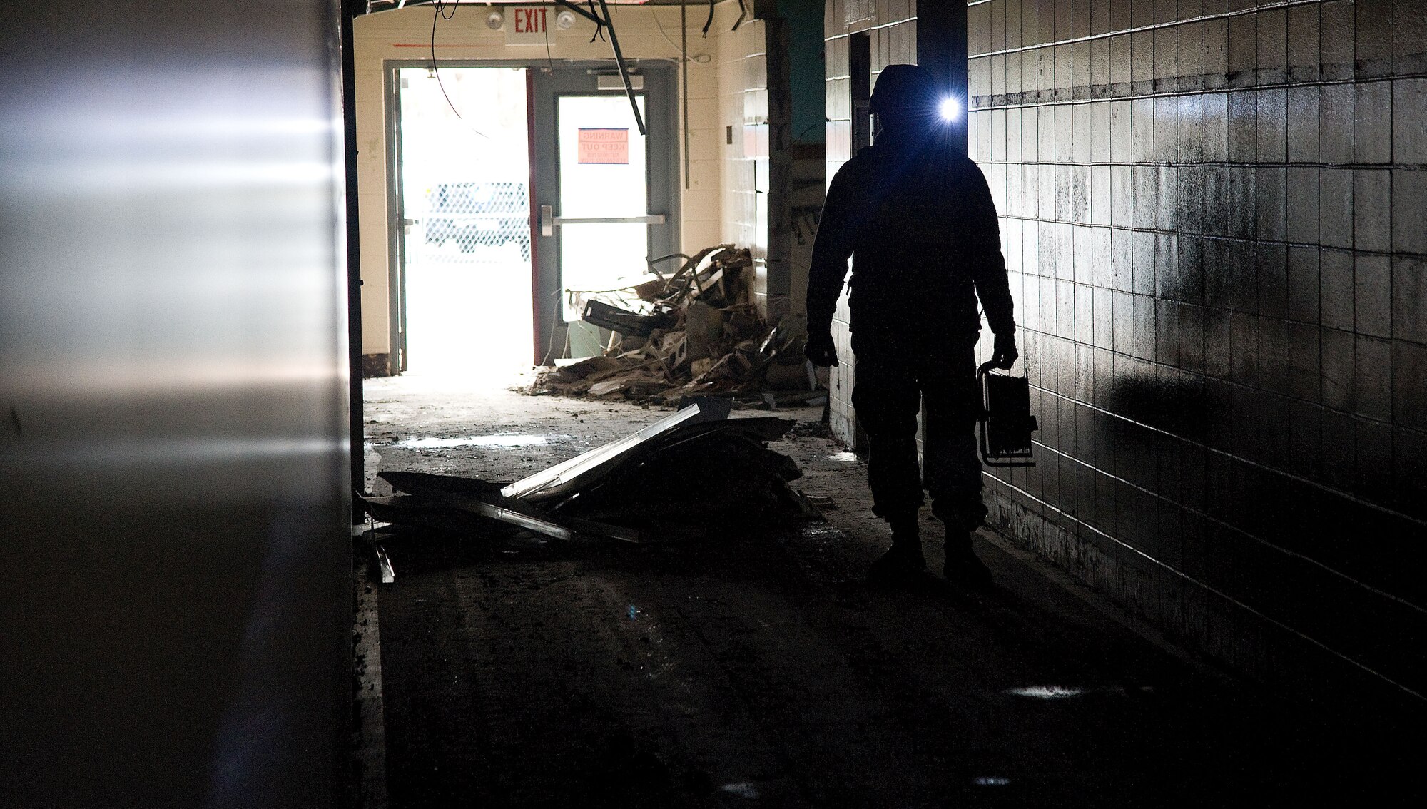 Senior Airman Gregg Lowry, a members of the 436th Civil Engineer Squadron, Explosive Ordnance Disposal (EOD) team, is partially silhouetted  while working inside a hallway of the former Arnold Elementary School during an EOD training event at Dover Air Force base, Del. on Feb. 7, 2013. Lowry has a Surefire tactical helmet light in-use to provide hands-free lighting while conducting critical mission tasks. The training allowed the Air Force EOD team to gain valuable training using live explosives during simulated events that mirror recent real-world scenarios encountered by EOD teams across the nation. The 436th CE Squadron also hosted regional law enforcement teams from the Delaware and New Jersey State Police. The civilian law enforcement and USAF teams exchanged ideas and best practices in the hands-on training to ensure all are safe and well prepared for the future. (U.S. Air Force photo/Greg L. Davis)     