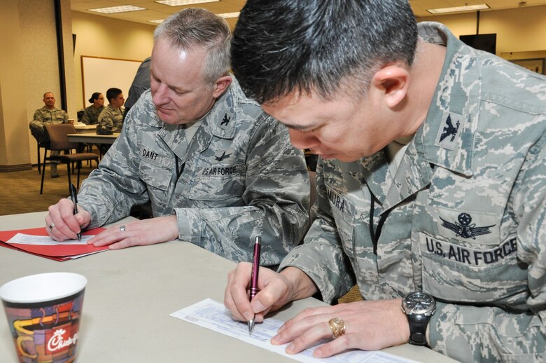 Col. Dan Dant, 460th Space Wing commander, and Col. Robert Uemura, 460th Mission Support Group commander, fill out pledge cards to donate to the Air Force Assistance Fund Feb. 8, 2013, at the Buckley AFB Chapel.  Team Buckley’s goal for the campaign is 50 percent member participation and more than $29,000 in donations. (U.S. Air Force photo by Staff Sgt. Nicholas Rau/Released)