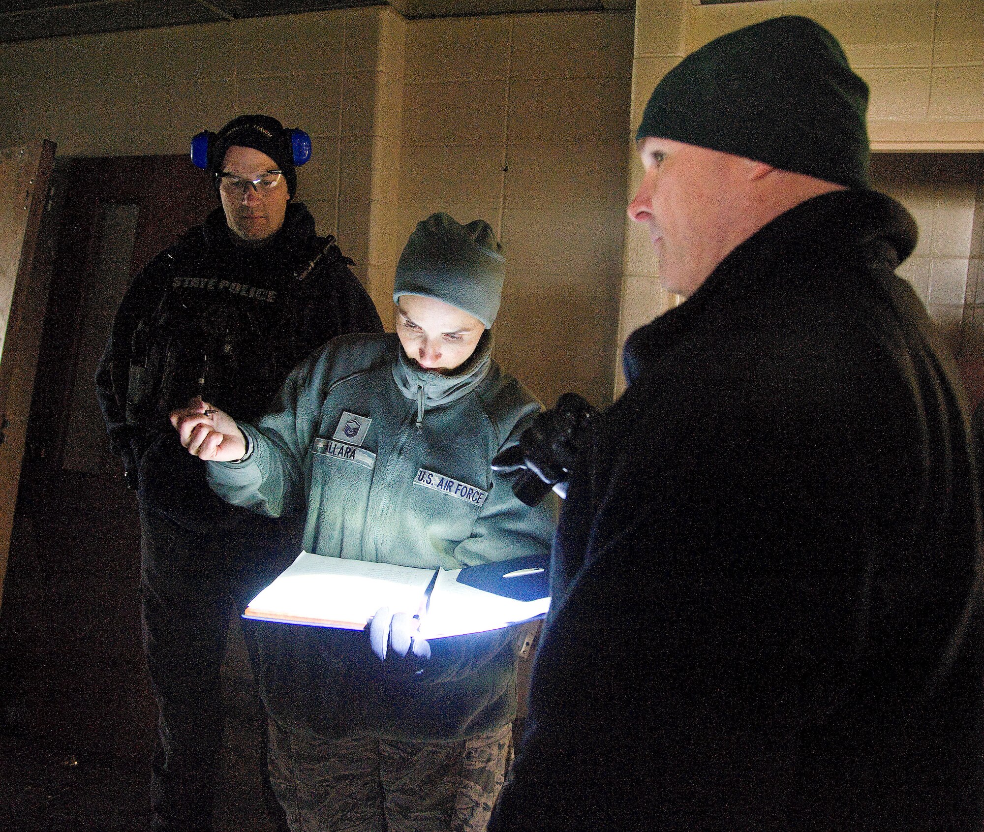 Air Force Master Sgt. Jennifer Allara (middle), 436th Civil Engineer Squadron Explosive Ordnance Disposal team, writes down information given to her by Sgt. Chris Ennis, Delaware State Police EOD team commander, during a training event at Dover Air Force base, Del. on Feb. 7, 2013. The training allowed the Air Force EOD team to gain valuable training using live explosives during simulated events that mirror recent real-world scenarios encountered by EOD teams across the nation. The 436th CE Squadron also hosted regional law enforcement teams from the Delaware and New Jersey State Police. The civilian law enforcement and Air force teams exchanged ideas and best practices in the hands-on training to ensure all are safe and well prepared for the future. USAF photo/Greg L. Davis   