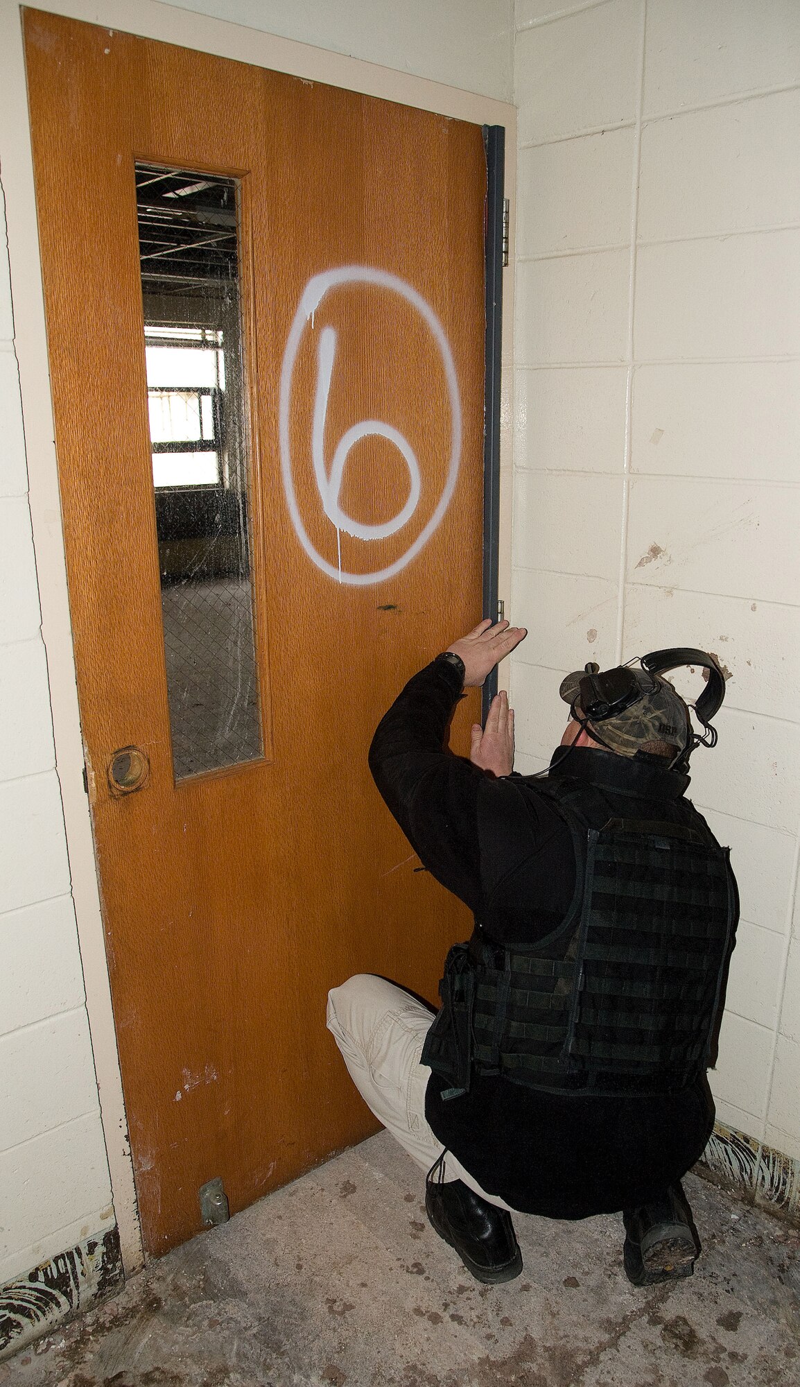An Explosive Ordnance Disposal technician places a door breaching explosive near the hinges of a solid wood door by  a regional police EOD team at Dover Air Force base, Del. on Feb. 7, 2013. Members of the 436th Civil Engineer Squadron conducted an Explosive Ordnance Disposal (EOD) training event at the base to allow both Air Force and regional police EOD teams to gain valuable training using live explosives during simulated events that mirror recent real-world scenarios encountered by EOD teams across the nation. The 436th CE Squadron teams from the Delaware and New Jersey State Police. The civilian law enforcement and USAF teams exchanged ideas and best practices in the hands-on training to ensure all are safe and well prepared for the future. USAF photo/Greg L. Davis