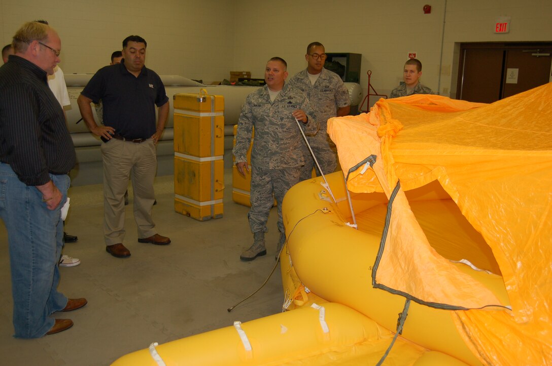 Master Sgt. Joe Cavazos III, shop chief for the 433rd AW Survival Shop, demonstrates the instant inflation of a 25-man life raft, one of several standard survival equipment items carried at all times by the C-5A Galaxy.  Demonstration was done for visiting guests from insurance giant USAA's Mortgage Division, who visited the shop and others on Feb. 7, 2013.  The shop is assigned to the 433rd Operations  Support Squadron, one of four squadrons that comprise the 433rd Operations Group at the 433rd Airlift Wing, (U.S. Air Force photo by Elsa Martinez)