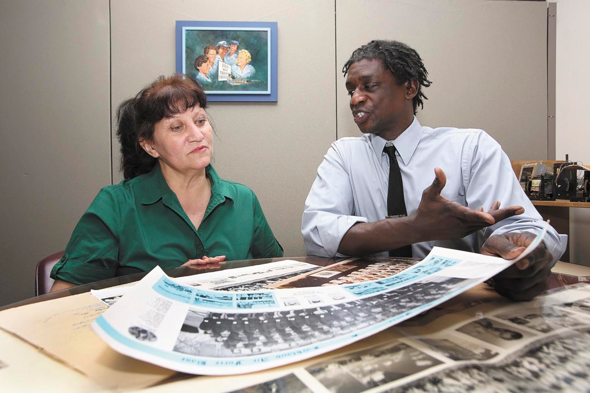 Minnie Martinez, 37th Training Wing Office of History and Research administrative assistant, looks through recent photo acquisitions with Tracy English, 37th TRW Office of History and Research chief. Martinez and English are compiling images of trainees who graduated from basic at JBSA-Lackland, as well as other U.S. Air Force training sites and overseas. According to English, Martinez has processed more BMT flight photos for the website than anyone else. Both are retired Air Force.  (u.S. Air Force photo by Robbin Cresswell)