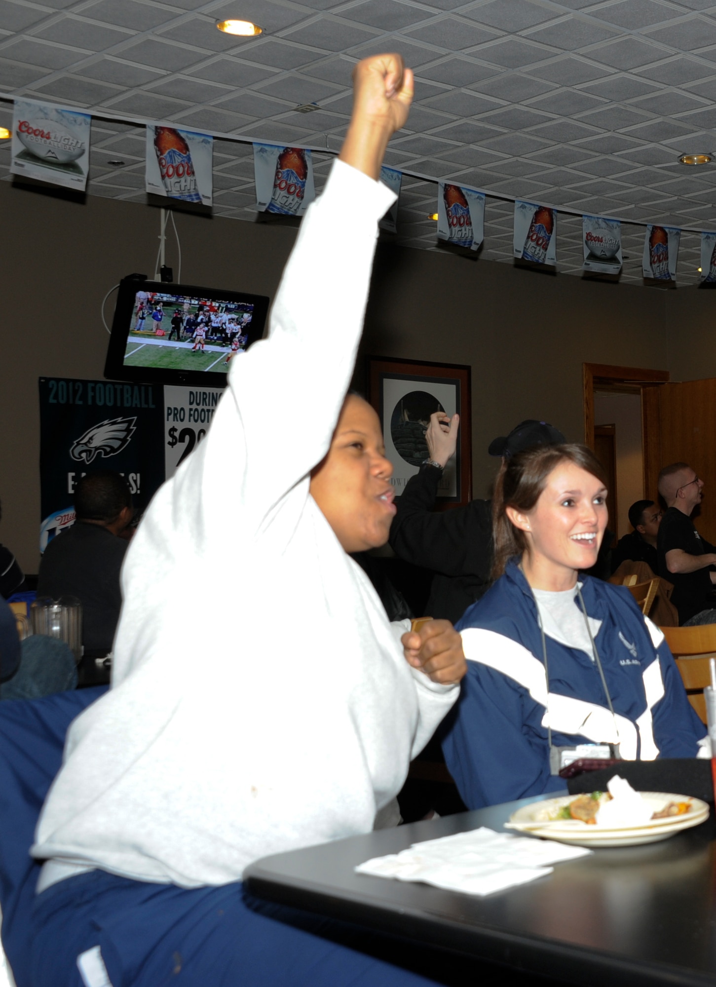 Capt. Capri Baptiste, left, and 1st Lt. Ryane Ulrich, right, both participating in mobilization training at Joint Base McGuire-Dix-Lakehurst, cheer during the Super Bowl viewing Feb. 3, 2013, at Pudgy's Sports Bar on JB MDL, N.J. The Airmen are both attending Combat Skills Training at JB MDL before they deploy to Afghanistan Feb. 7. Baptiste is stationed at Shaw Air Force Base, S.C. Ulrich is stationed at Offutt Air Force Base, Neb. (U.S. Air Force photo by 2nd Lt. Alexis McGee/Released)