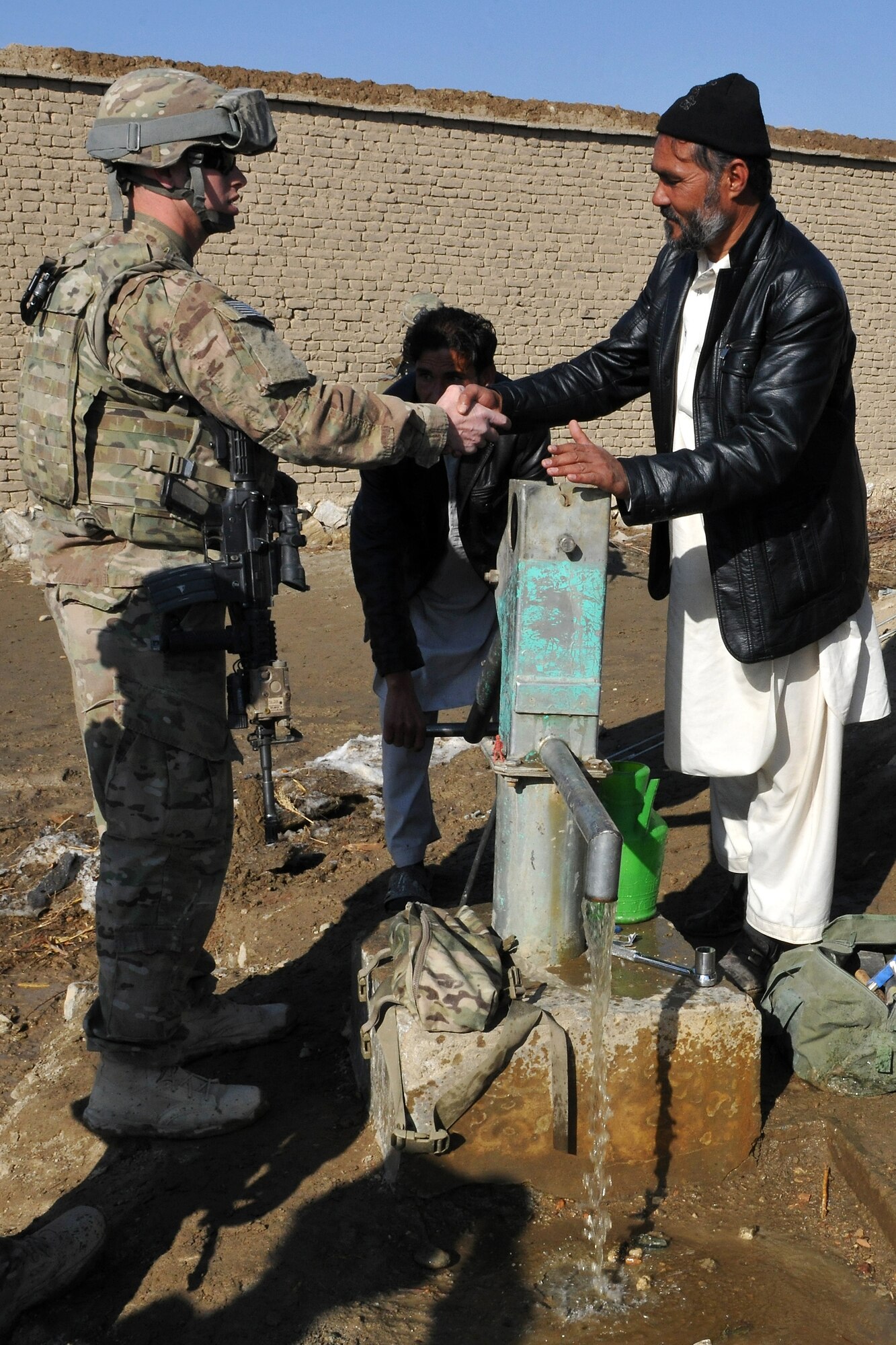 U.S. Airmen and local Afghan elders gather around the recently fixed water well in the heart of a small village near Bagram Airfield, Afghanistan, on Jan. 26, 2013. Together they traded ideas on how to fix the pump and bring the fresh groundwater back to the village. (U.S. Air Force photo/Senior Airman Chris Willis)
