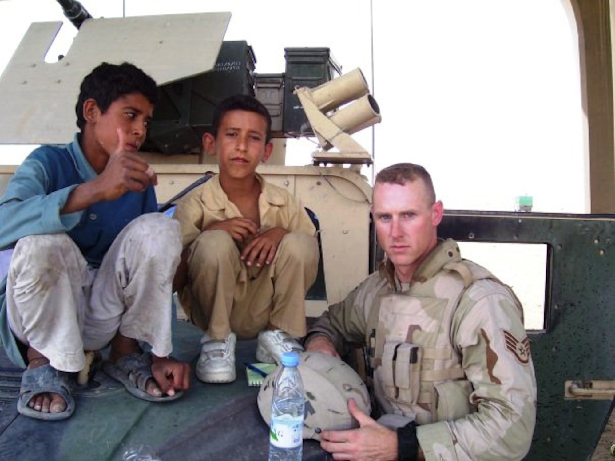 Tech. Sgt. Francis Woznick, 366th Security Forces Squadron, and two Iraqi children take a break on the hood of his Humvee. Woznick said he remembers well the day he responded to a traffic accident to find an Iraqi boy dying. “He turned grey in front of me,” said Woznick, who has no children of his own but he often thinks of his younger sister who still lives at his childhood home in Seneca Falls, N.Y. “There was nothing I could do.” (Courtesy photo)