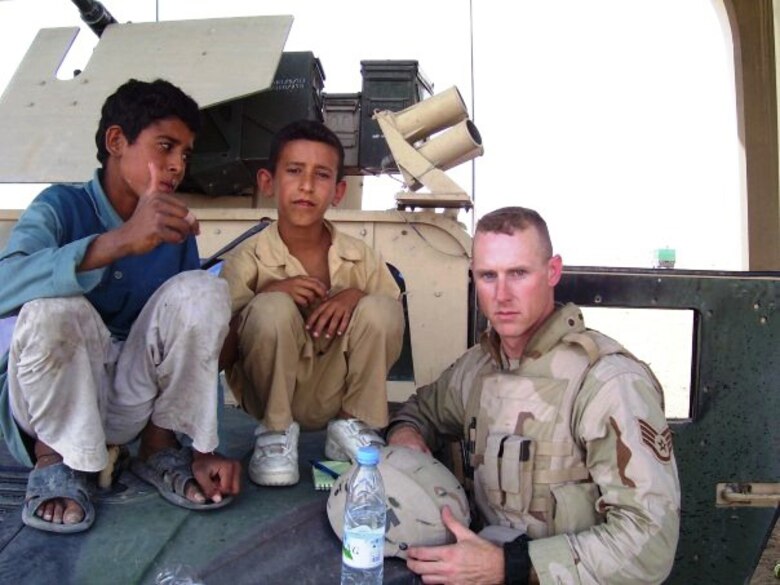 Tech. Sgt. Francis Woznick, 366th Security Forces Squadron, and two Iraqi children take a break on the hood of his Humvee. Woznick said he remembers well the day he responded to a traffic accident to find an Iraqi boy dying. “He turned grey in front of me,” said Woznick, who has no children of his own but he often thinks of his younger sister who still lives at his childhood home in Seneca Falls, N.Y. “There was nothing I could do.” (Courtesy photo)