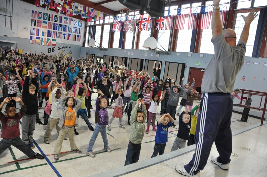 Matt Soughers, Travis Elementary School physical education teacher, leads students in a stretch during a morning exercise session named Team Time at Travis Air Force Base, Calif., Feb. 5, 2013. Preschool through sixth-grade students assemble in the gym four days per week for the 15-minute workout to start the day. (U.S. Air Force photo/Nick DeCicco)
