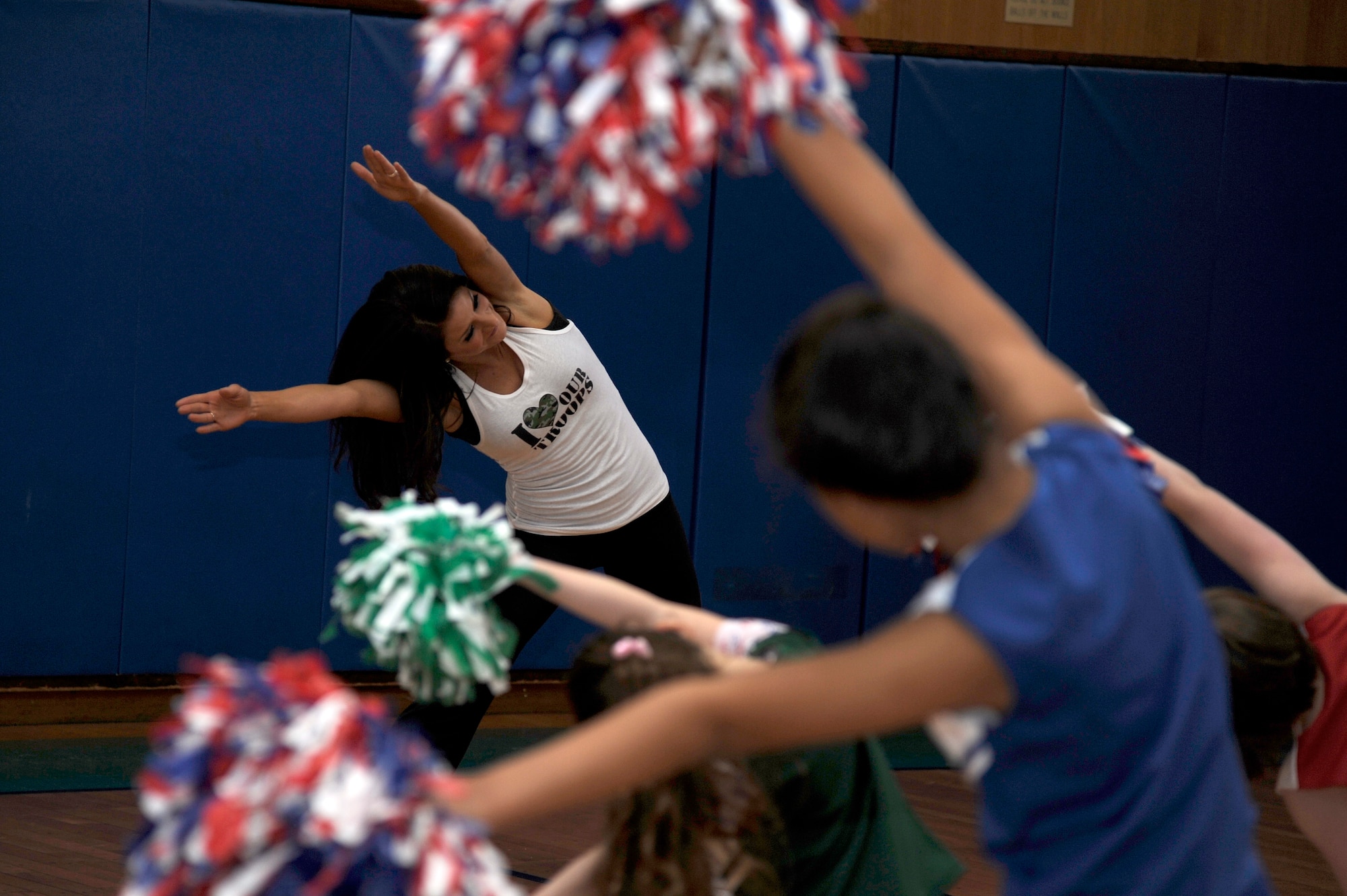 Tara, Denver Broncos cheerleader, leans to the left as Misawa youth mirror her actions during a cheer clinic at Misawa Air Base, Japan, Feb. 4, 2013. The two cheerleaders along with two players from the Washington Redskins, visited the base to show their appreciation to those serving. (U.S. Air Force photo by Tech. Sgt. Marie Brown)