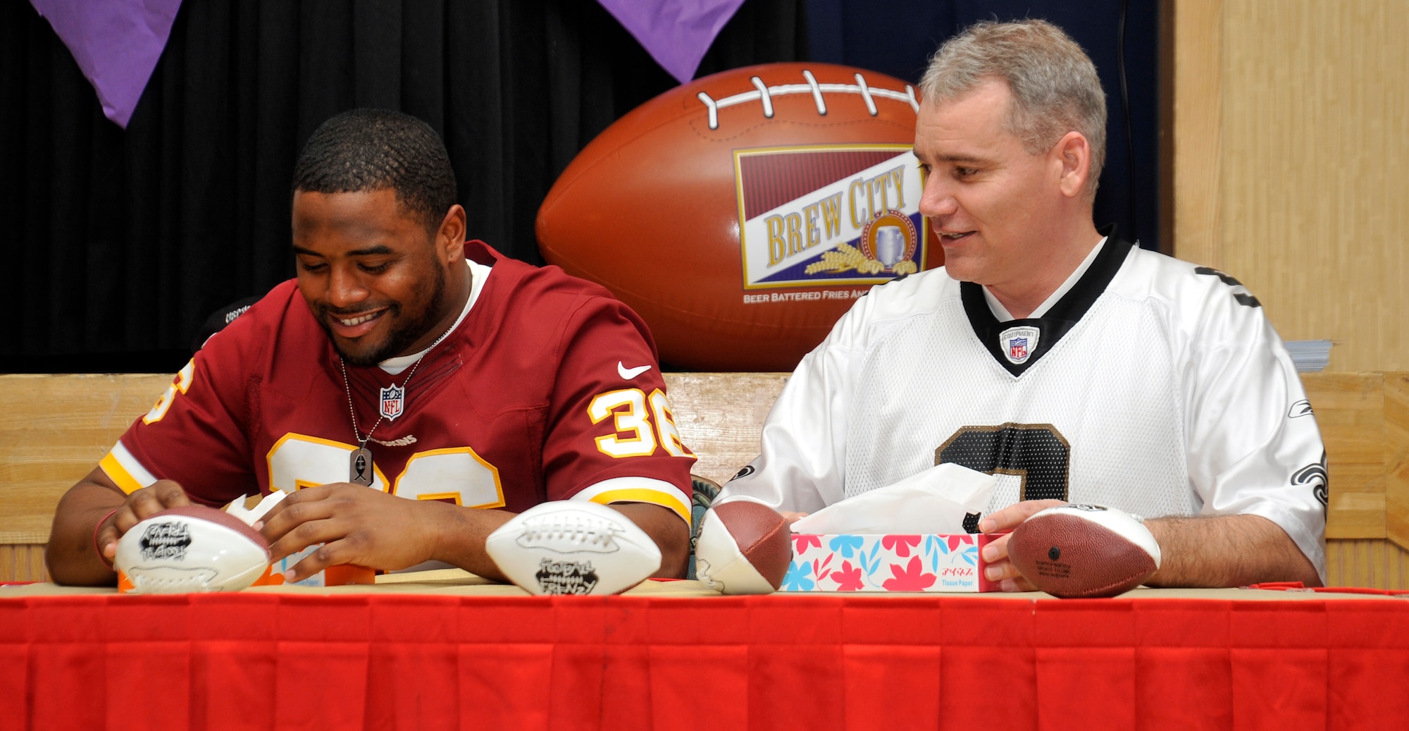 Darrel Young, left, Washington Redskins fullback, and Chief Master Sgt. James Laurent, 35th Fighter Wing command chief, take part in a competition at Misawa Air Base, Japan, Feb. 5, 2013. The objective was to see who could pull the most tissues out of a box in one minute. The purpose of the NFL’s stars visit was to give back to service members stationed at Misawa. (U.S. Air Force photo by Airman 1st Class Zachary Kee)