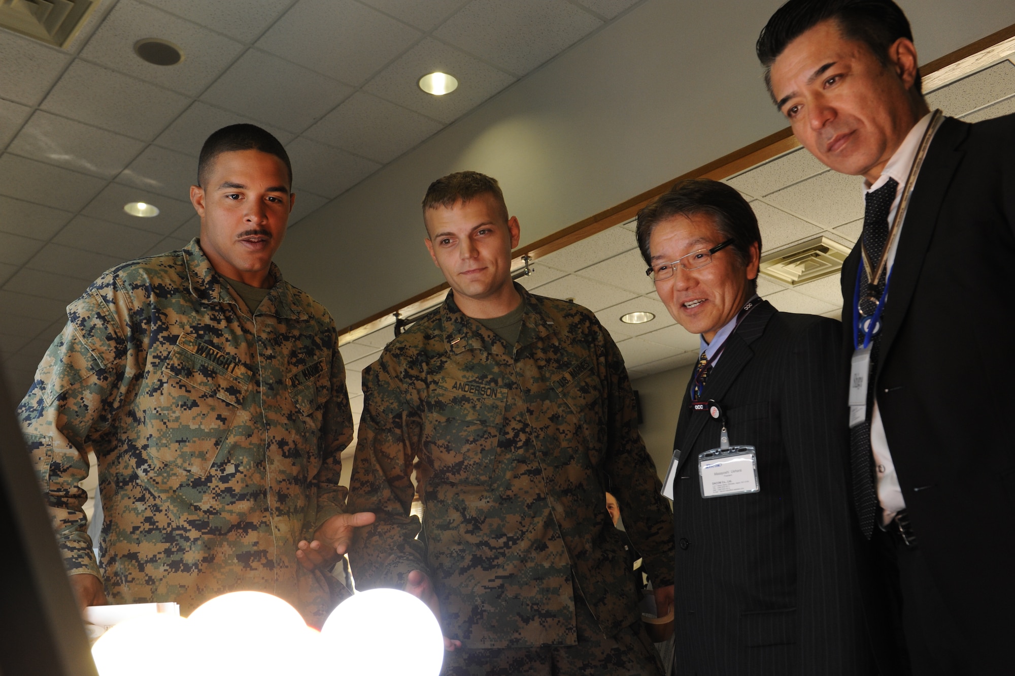 U.S. Marine Corps 1st Lt. Carl Anderson, 3rd Maintenance Battalion supply officer, and Cpl. Richard Wright, 3rd Maintenance Battalion administrative NCO, ask DACOM company employees questions about their light display at the third-annual Okinawan first vendor showcase on Kadena Air Base, Japan, Feb. 7, 2013. More than 20 vendors came to the event to show various products their companies have to offer. (U.S. Air Force photo/Airman 1st Class Malia Jenkins)