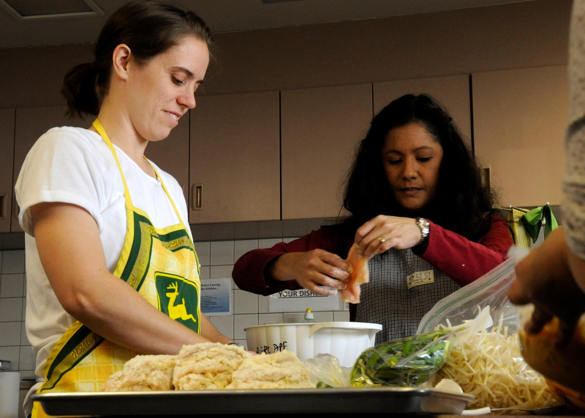 Michelle Hackett, left, and Cheryl Ray glaze and coat chicken for a Chinese cooking class in the Airman and Family Readiness Center kitchen at Misawa Air Base, Japan, Feb. 4, 2013. During the class, attendees learned to make Chinese lemon chicken. (U.S. Air Force photo by Airman 1st Class Kenna Jackson)