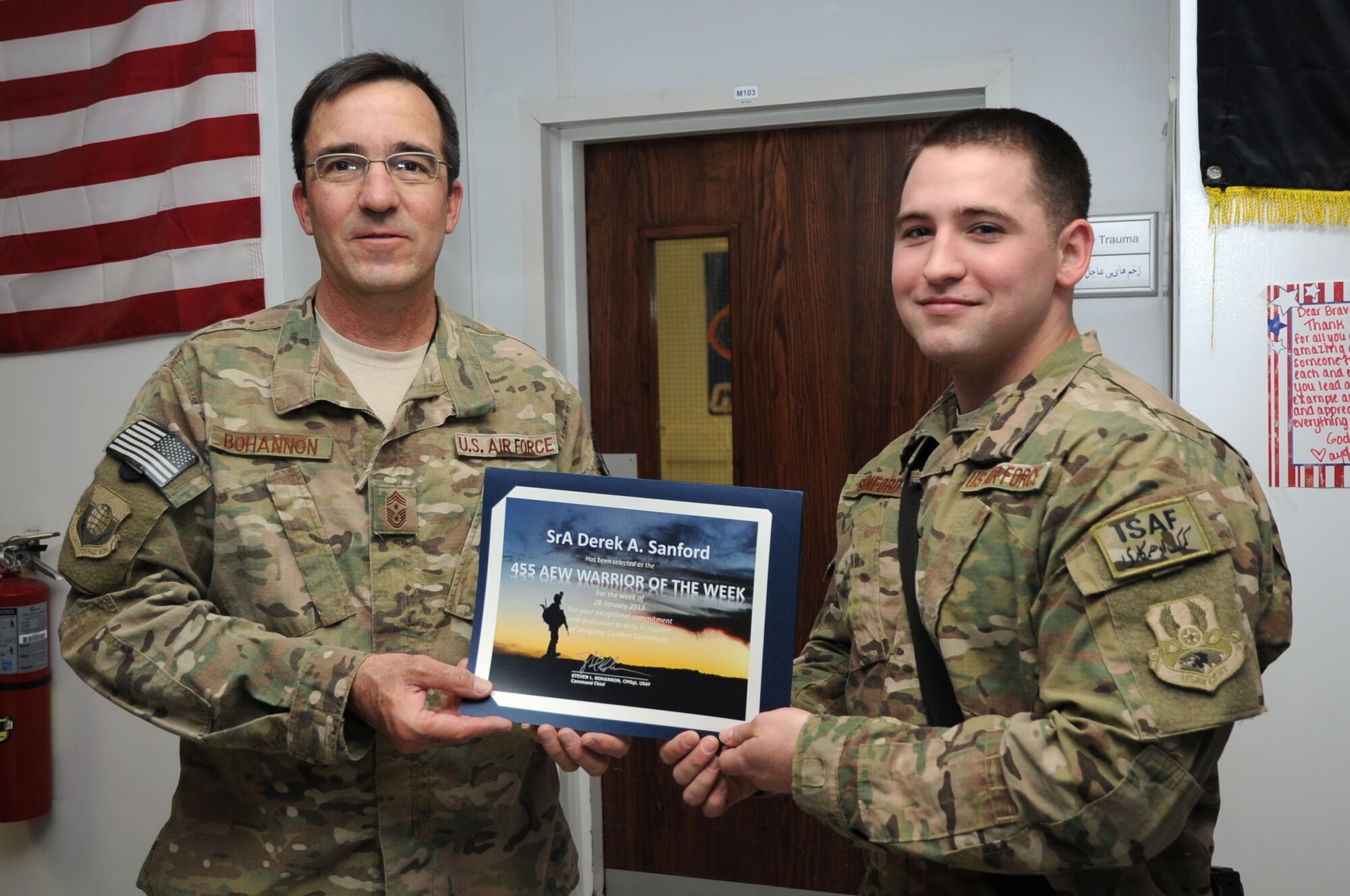 Chief Master Sgt. Steve Bohannon, Command Chief Master Sergeant of the 455th Air Expeditionary Wing, presents the "Warrior of the Week" award to Senior Airman Derek Sanford, 455th Expeditionary Medical Operations Squadron public health technician, on Bagram Airfield, Afghanistan, Feb. 7, 2013. Sanford helps safeguard the base population by ensuring food safety at all dining facilities on base. (U.S. Air Force photo/Staff Sgt. David Dobrydney)