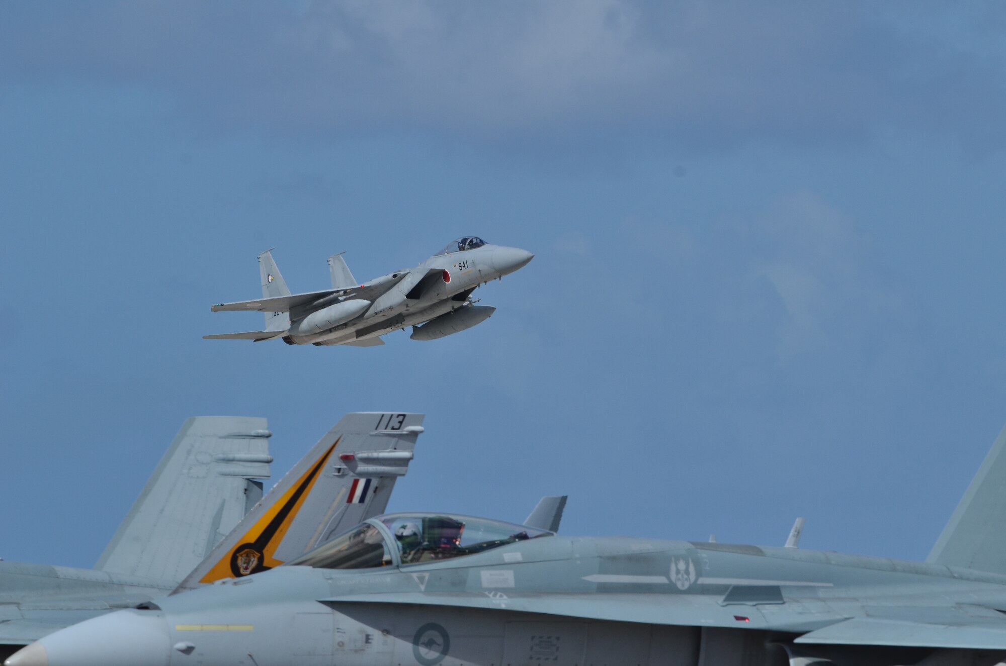 A Japan Air Self Defense F-15J takes off as Royal Australian Air Force Airmen start up their F/A-18 Hornets on the Andersen Air Force Base, Guam flight line during Cope North 2013 Feb 8. 2013. Cope North is an annual air combat tactics, humanitarian assistance and disaster relief exercise designed to increase the readiness and interoperability of the U.S. Air Force, Japan Air Self-Defense Force and Royal Australian Air Force. (U.S. Air Force photo by Staff Sgt. Alex Montes/RELEASED)