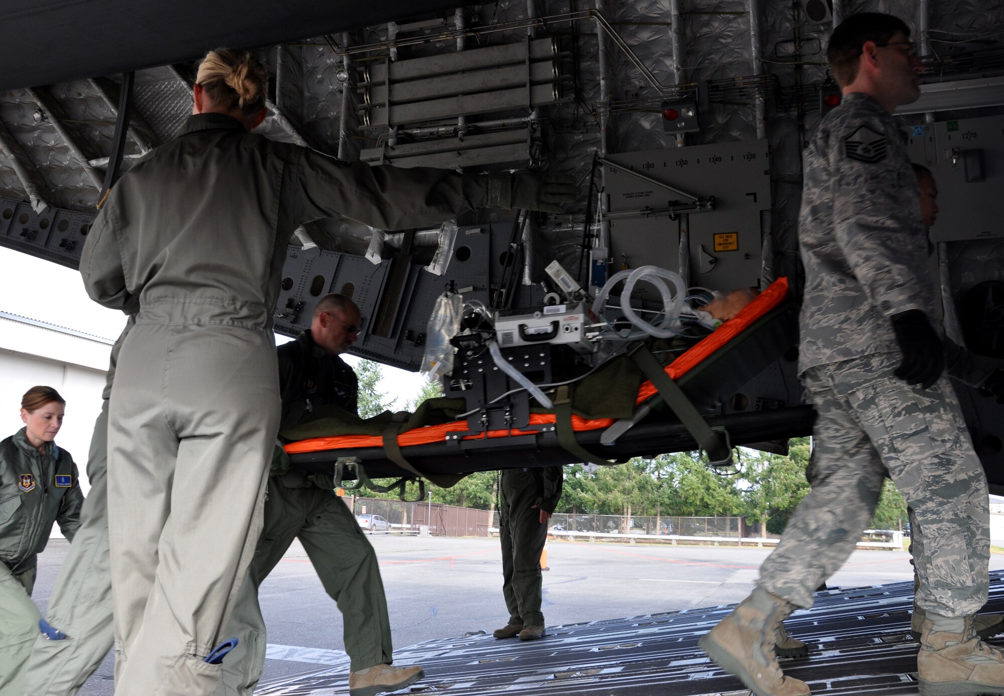 A team of Airmen from the 446th Aeromedical Staging Squadron and the 446th Aeromedical Evacuation Squadron carry a model victim on a litter onto a C-17 Globemaster III Feb. 9 at the new 446th ASTS building. The teams are demonstrating the type of training they will be able to accomplish with ASTS' new facility on the flight line. (U.S. Air Force Photo/Airman 1st Class Madelyn McCullough)