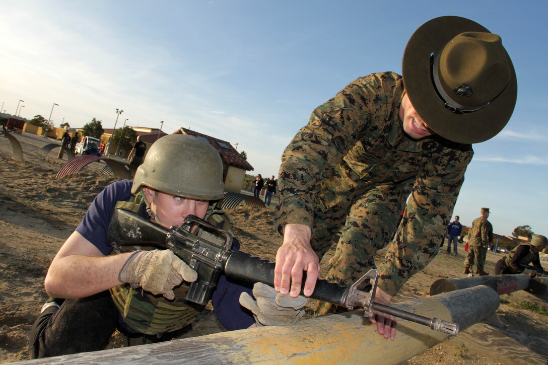 Senior drill instructor Staff Sgt. David Gentry shows a teacher from Recruiting Station Kansas City how to properly hold a dummy rifle while going through the bayonet assault course during an educators workshop Jan. 29. For additional imagery from the event, visit www.facebook.com/rstwincities. 