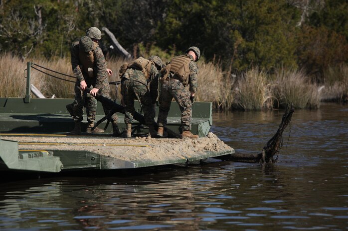 Marines with Bridge Company, 8th Engineer Support Battalion, 2nd Marine Logistics Group remove a tree from the path of an improved ribbon bridge, which was rafted up river in three parts, during a training exercise aboard Camp Lejeune, N.C., Jan 29, 2013. This type of bridge is frequently used for quick movement of troops and gear across bodies of water.