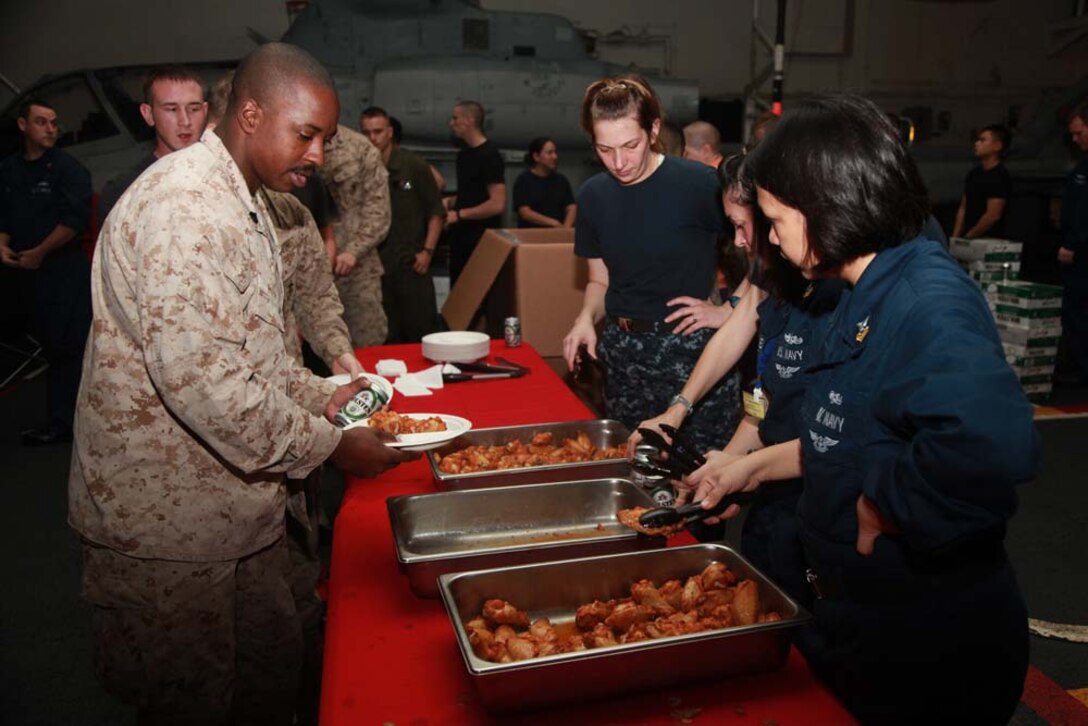 Sergeant Michael B. Peeks, communications technician, Command Element, 15th Marine Expeditionary Unit, gets food before watching Super Bowl XLVII during the Super Bowl party held in the hangar bay of the USS Peleliu, Feb. 4. The ship hosted a Super Bowl party for its Marines and sailors as a way to help them decompress and enjoy some of the comforts of home while being forward deployed. The 15th MEU is deployed as part of the Peleliu Amphibious Ready Group as a U.S. Central Command theater reserve force, providing support for maritime security operations and theater security cooperation efforts in the U.S. 5th Fleet area of responsibility. Peeks, 25, is from Chicago.