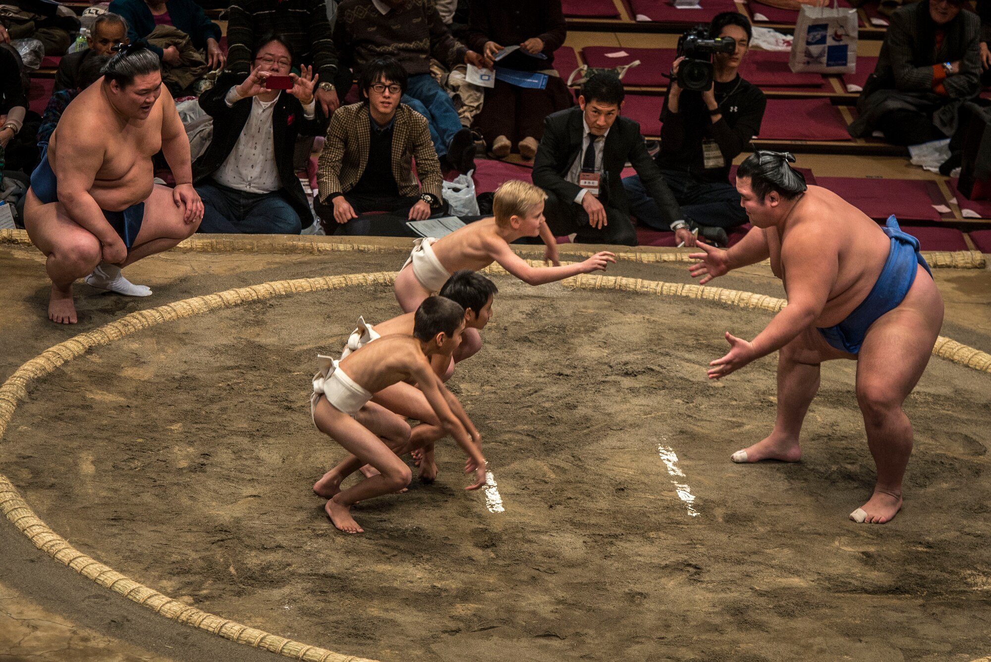 YOKOTA AIR BASE,Japan--A team of three children charge a poised Sumo wrestler during a children’s Sumo demonstration between bouts during the Grand Sumo Tournament at the Ryogoku Kokugikan Sumo Hall in Tokyo, Feb. 10, 2013. Thanks to the Yokota Air Base’s Information, Tickets and Travel office, Yokota Airmen had the unique opportunity to experience Sumo first-hand. (U.S. Air Force photo by Capt. Raymond Geoffroy)